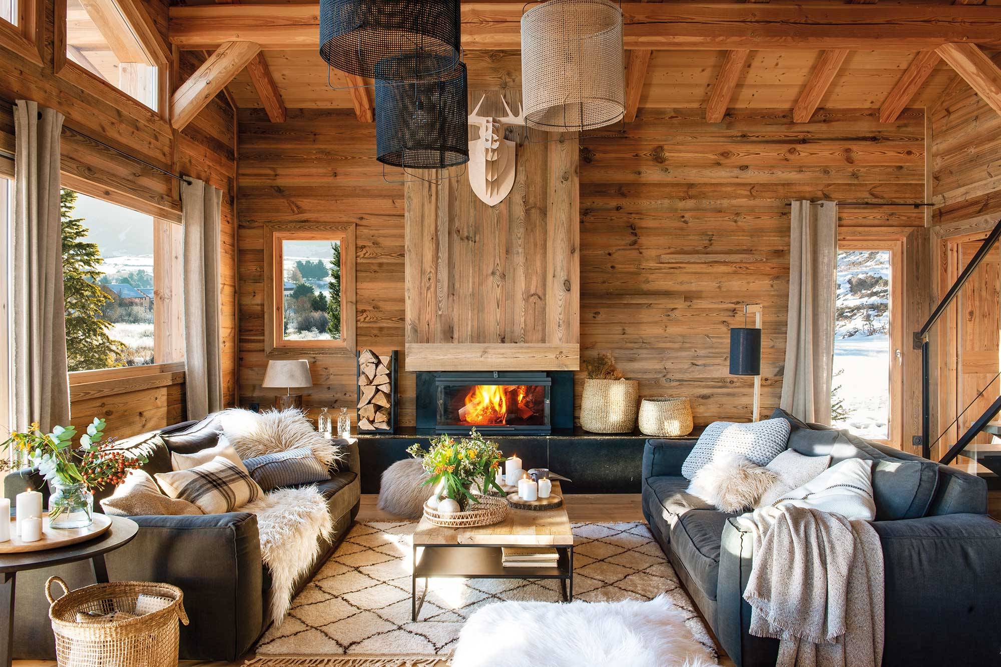 Salón de casa de montaña revestido de madera con chimenea y dos sofás enfrentados_00517193