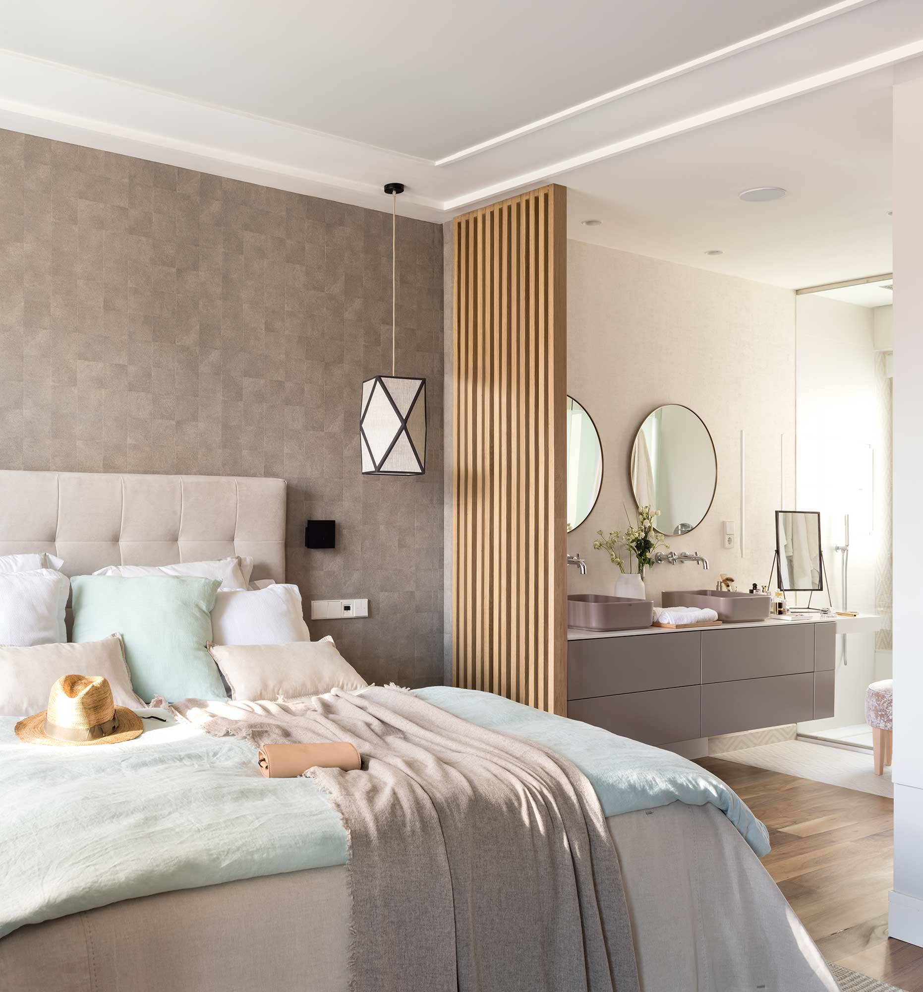 Dormitorio con pared con papel pintado y celosía de madera que separa del baño. 