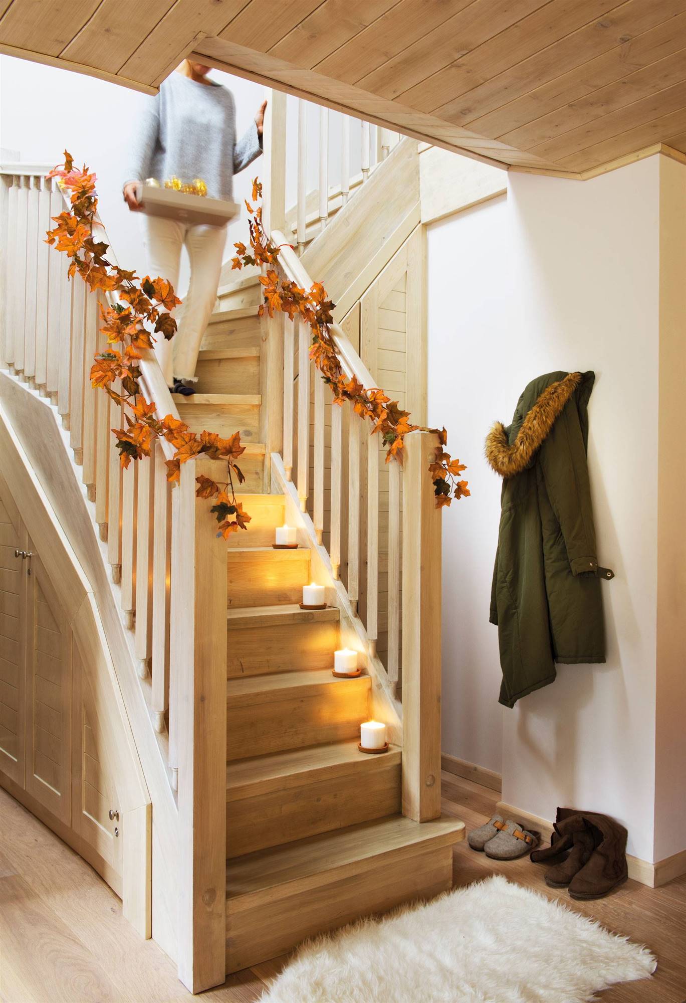 Escalera decorada con guirnalda navideña de hojas secas de otoño.