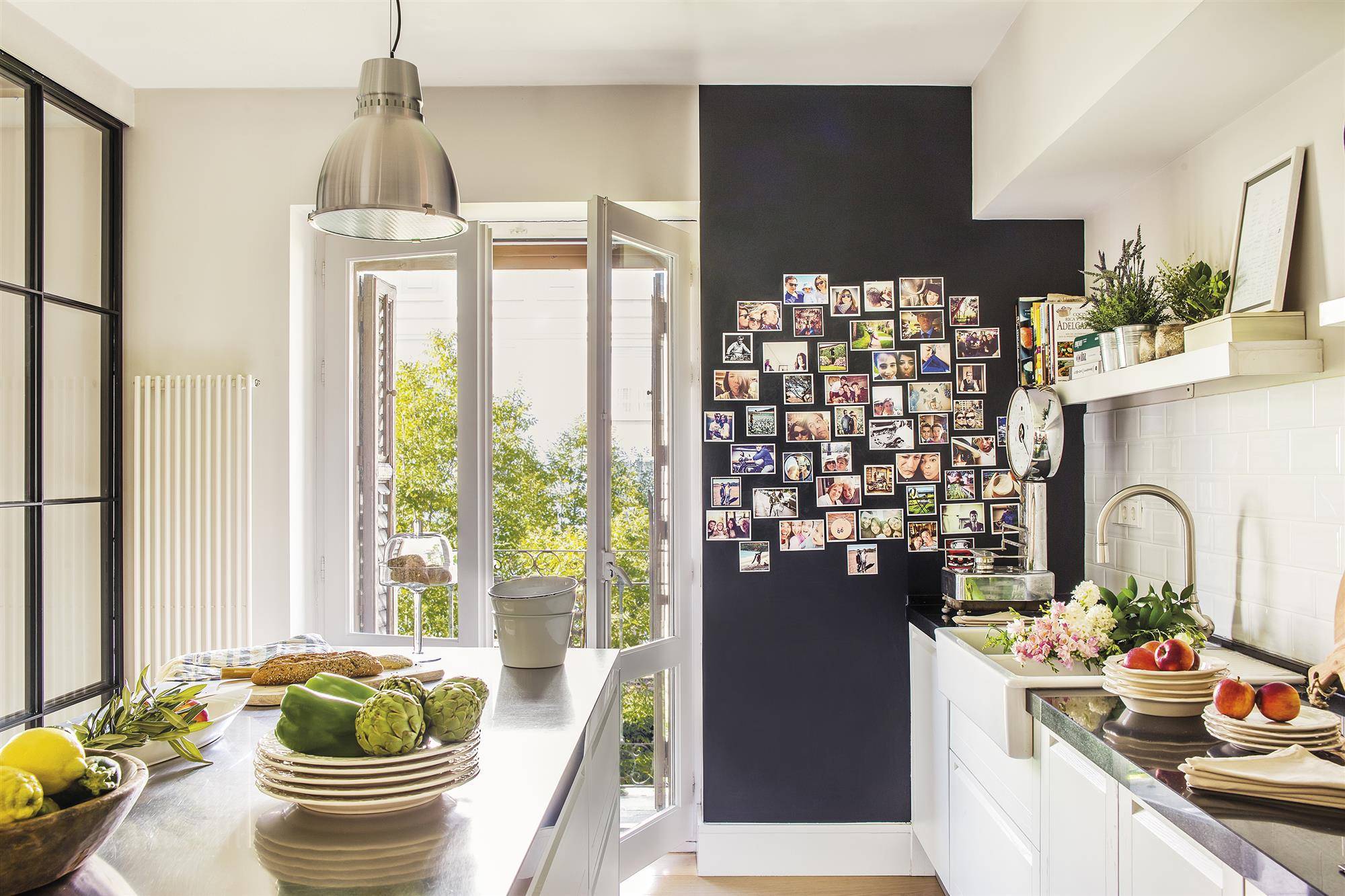 Cocina en blanco en finca regia con pared en negro decorada con fotos