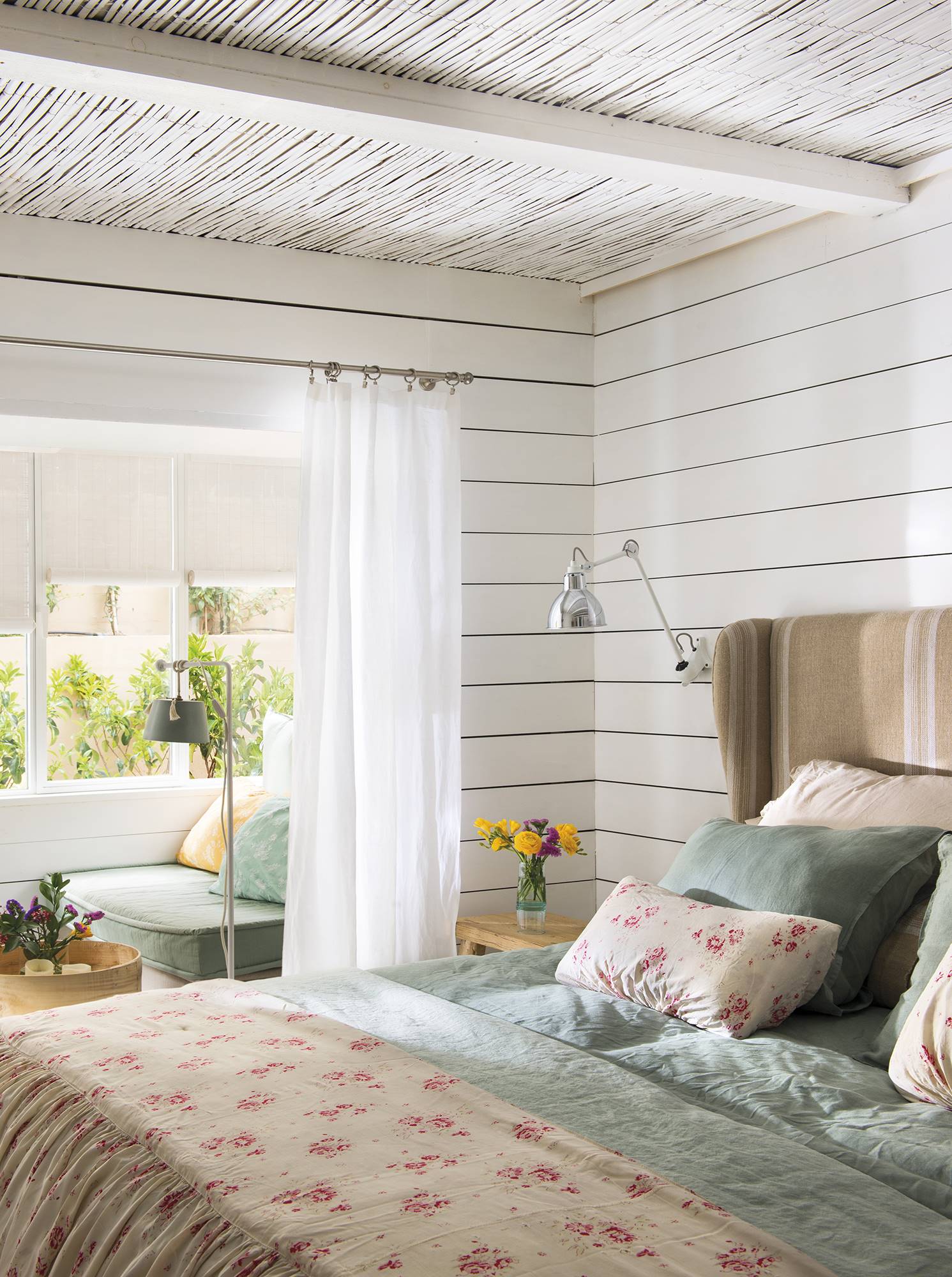 Dormitorio blanco con paredes de lamas de madera abierto al salón