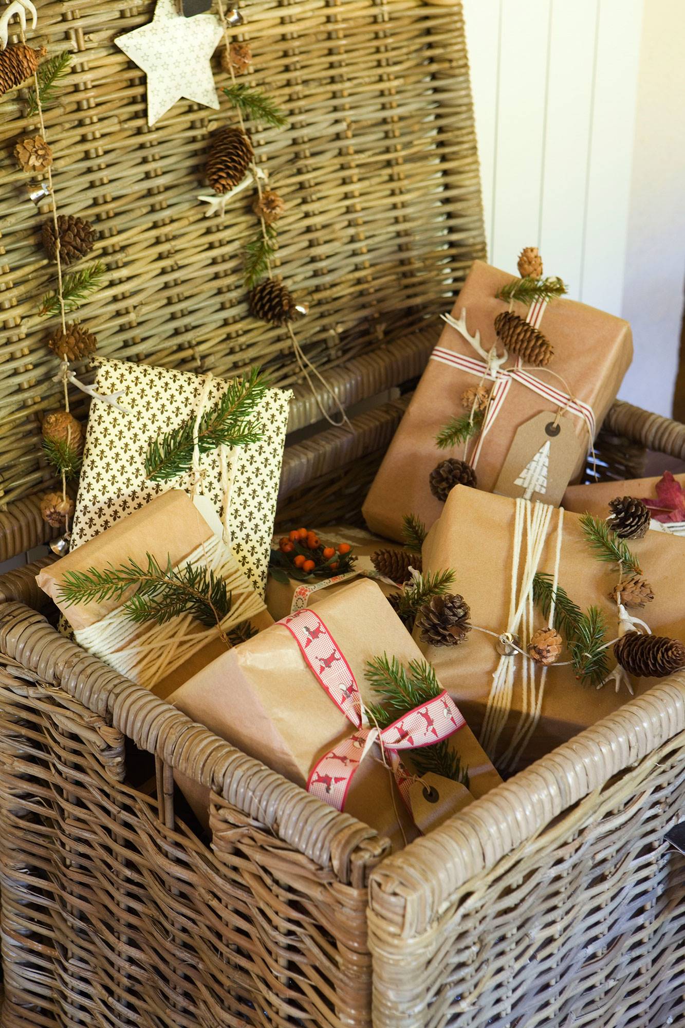 Detalle de cesto de fibras con regalos de Navidad decorados con piñas y motivos vegetales