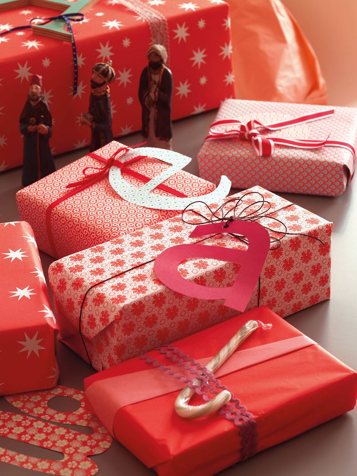 Detalle de regalos de Navidad con papeles en rojo y letras hechas con cartón