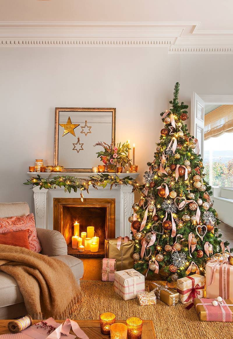 Salón decorado con un árbol de Navidad con adornos rosas y dorados.  