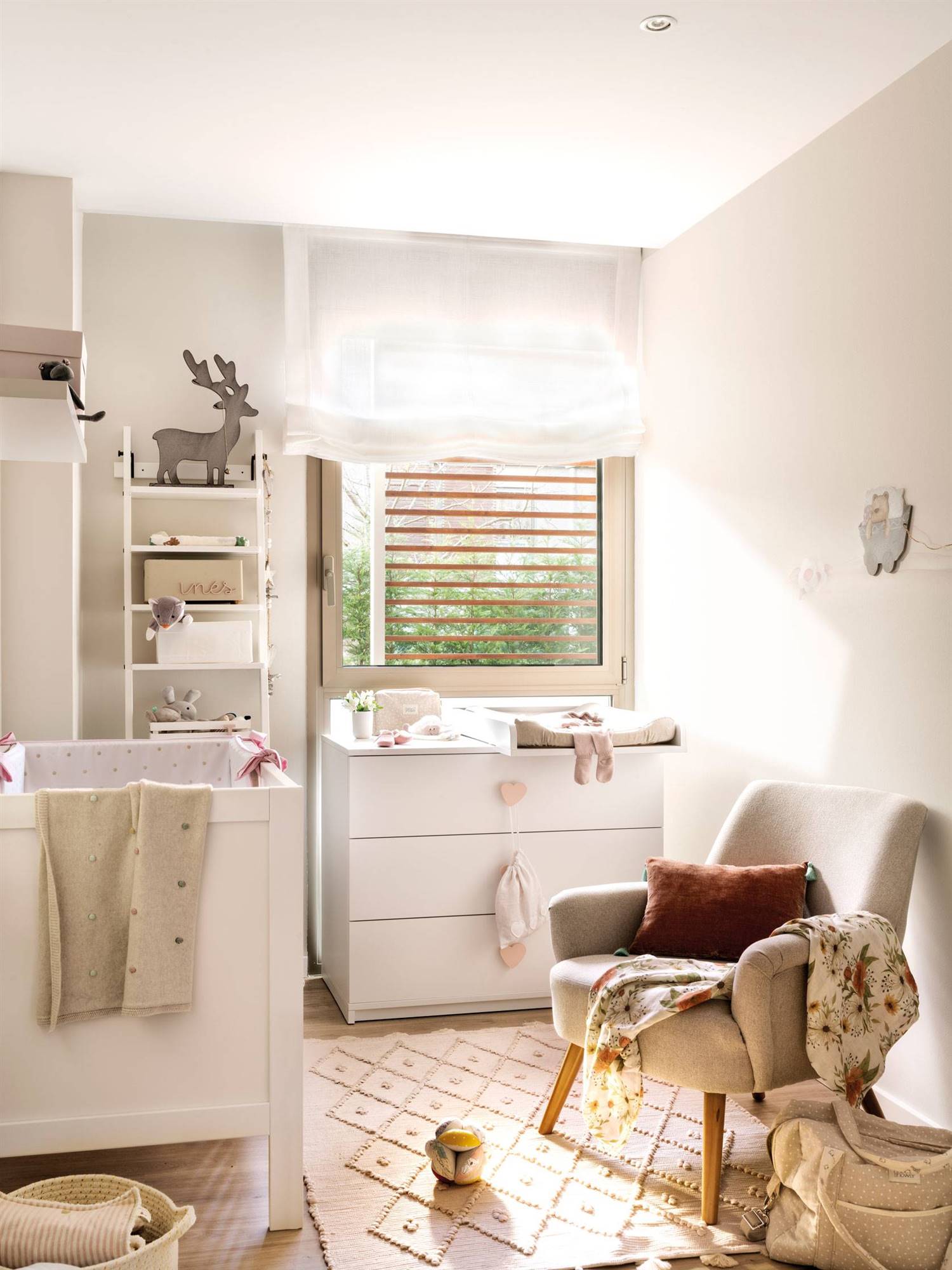 Habitación de bebé en blanco con cuna, cambiador, estantería, butaca y alfombra-522547