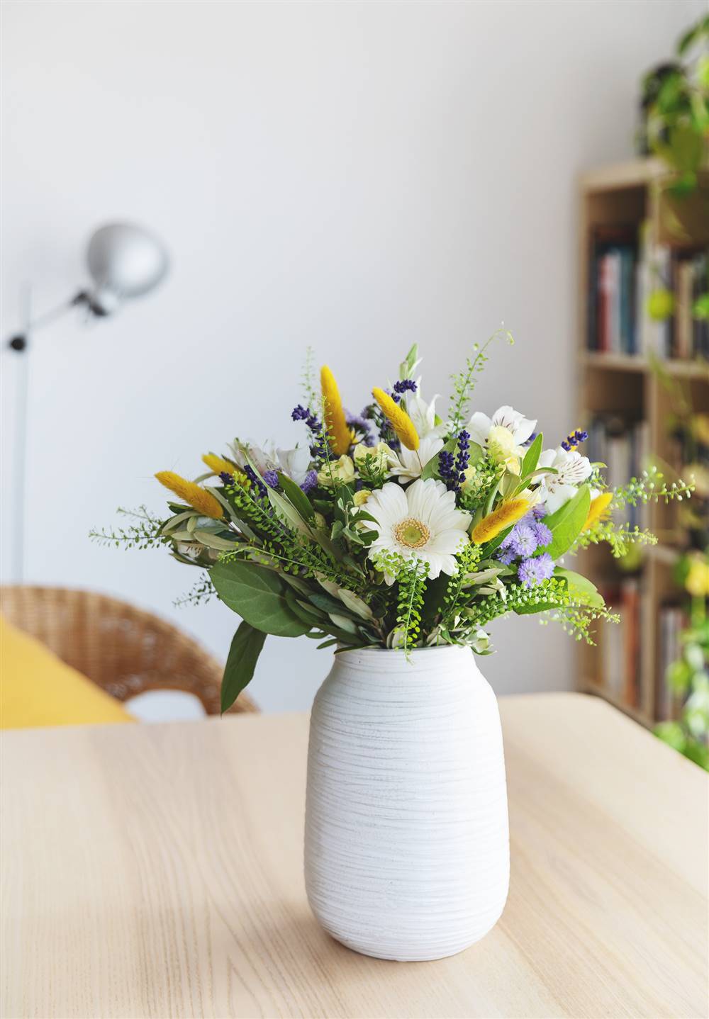Jarrón cilíndrico de cerámica blanca con ramo de flores blancas, amarillas y violetas