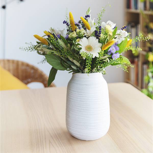 Jarrón cilíndrico de cerámica blanca con ramo de flores blancas, amarillas y violetas