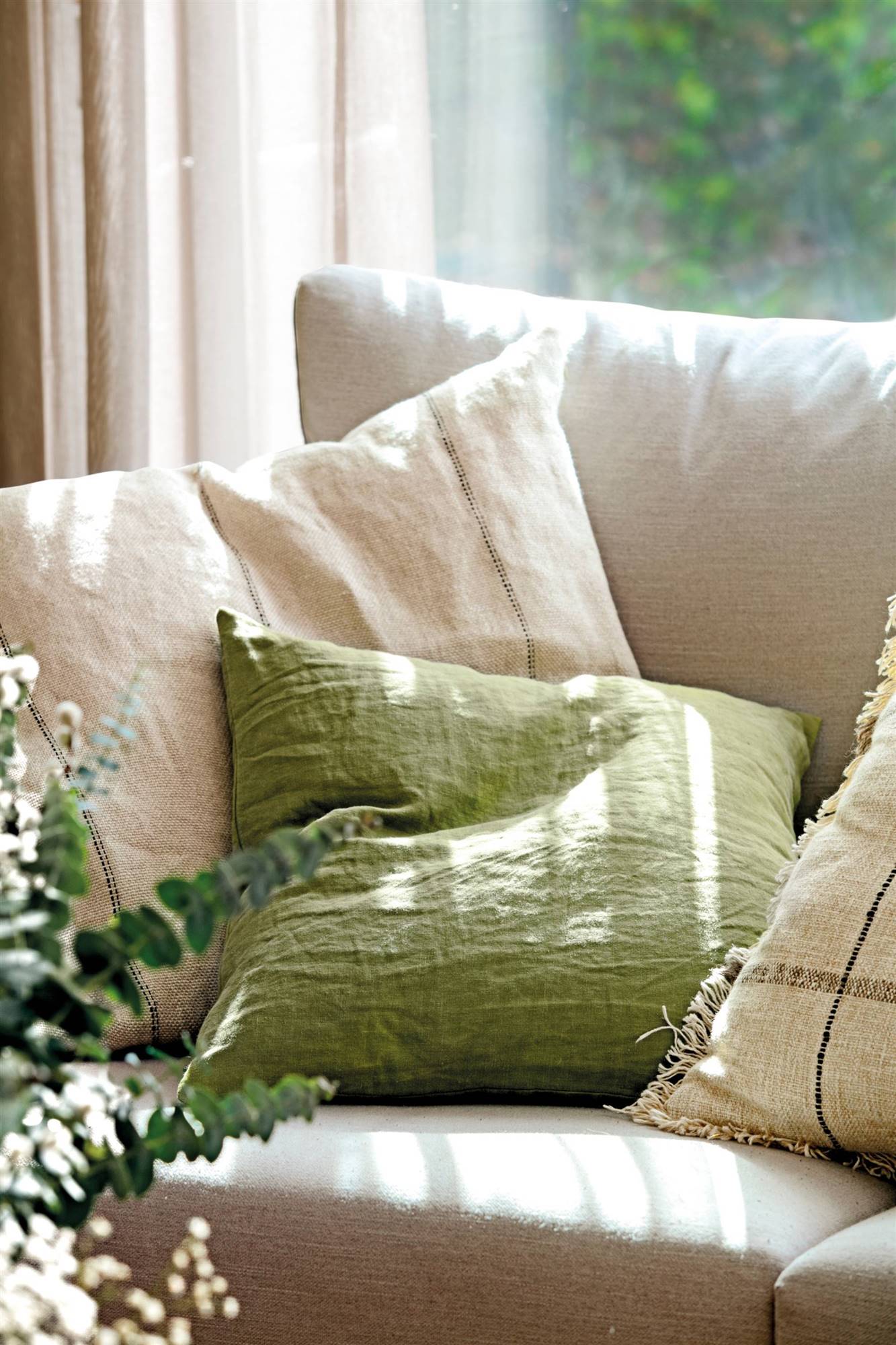 Sofá blanco con cojines de lino verdes y blancos. 