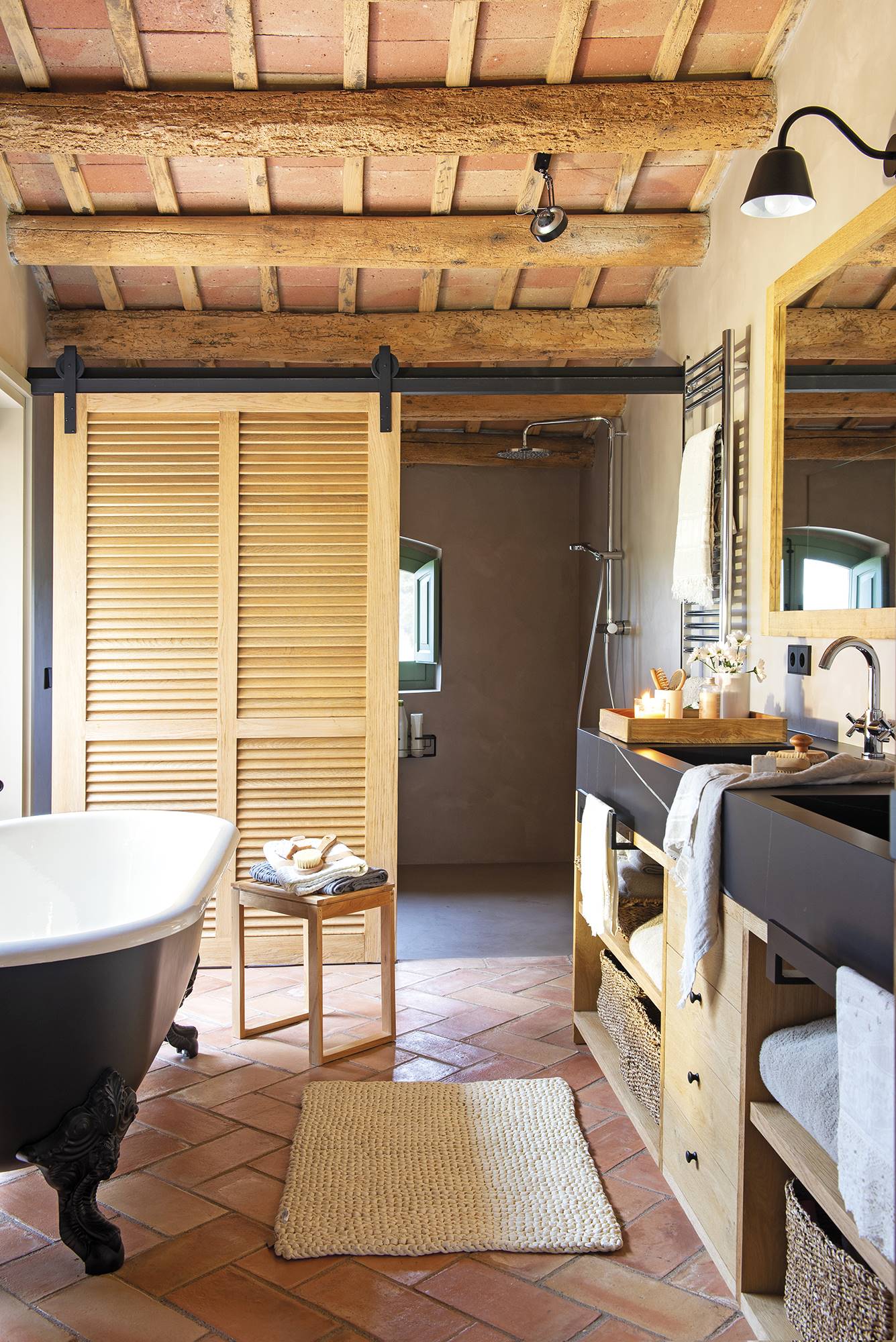 Baño de estilo rústico con bañera y puerta de granero. 
