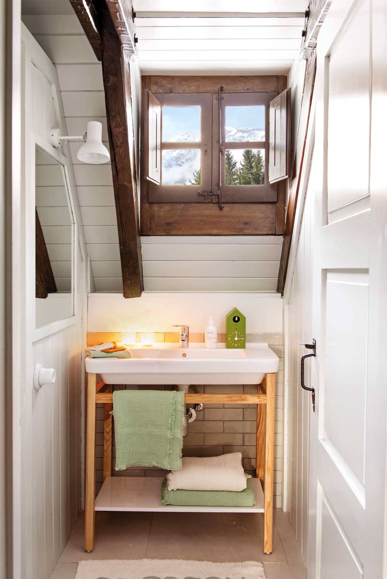 Baño pequeño y estrecho abuhardillado con ventana de madera. 
