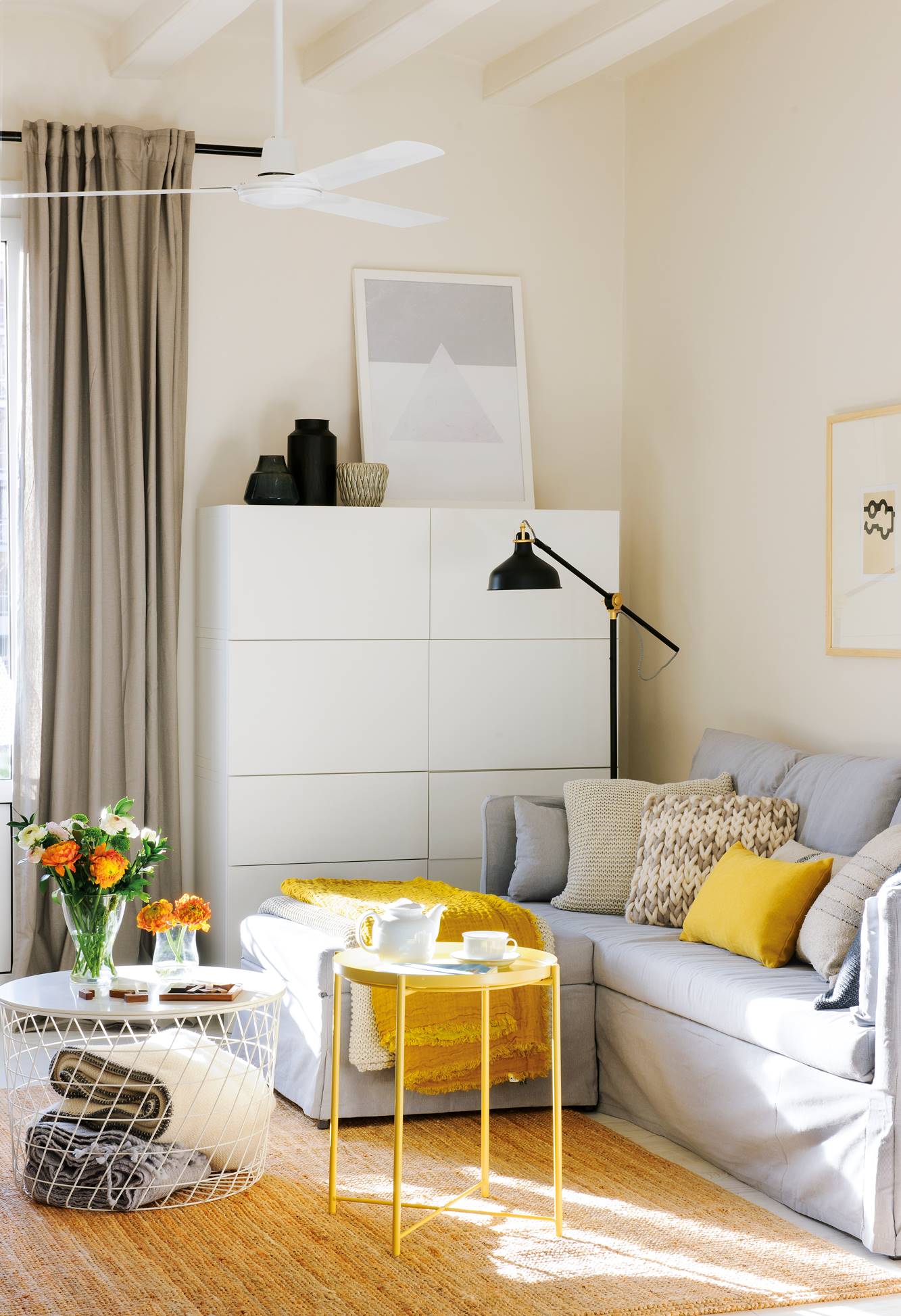 Salón con sofá con chaise longue, mesa con almacenaje y mesa auxiliar amarilla. 