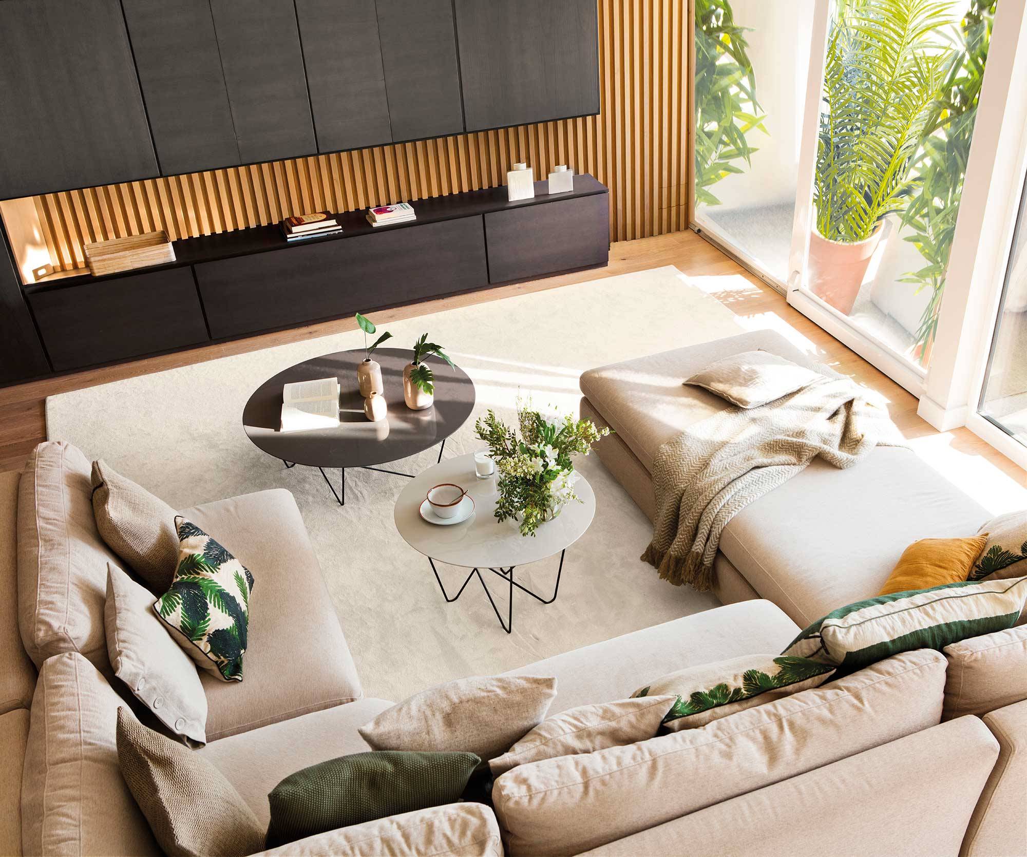 Vista cenital de salón con sofá modular y mueble del salón de madera y negro.