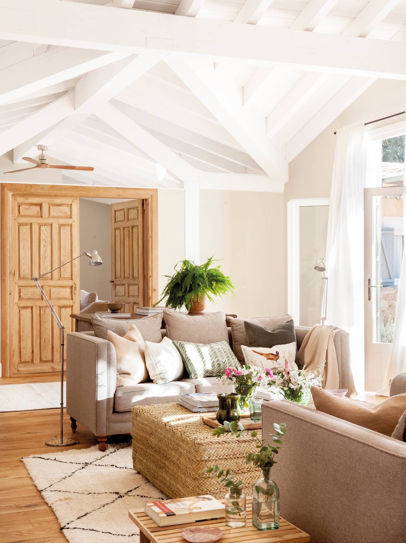 Salón blanco con techo de vigas blancas y sofá de lino con mesa de centro de fibras 00513397