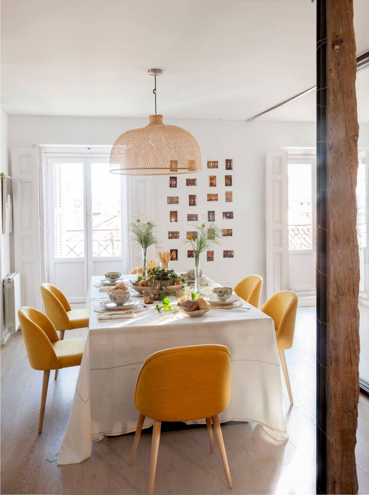 Comedor con sillas amarillas y pared con fotos. 