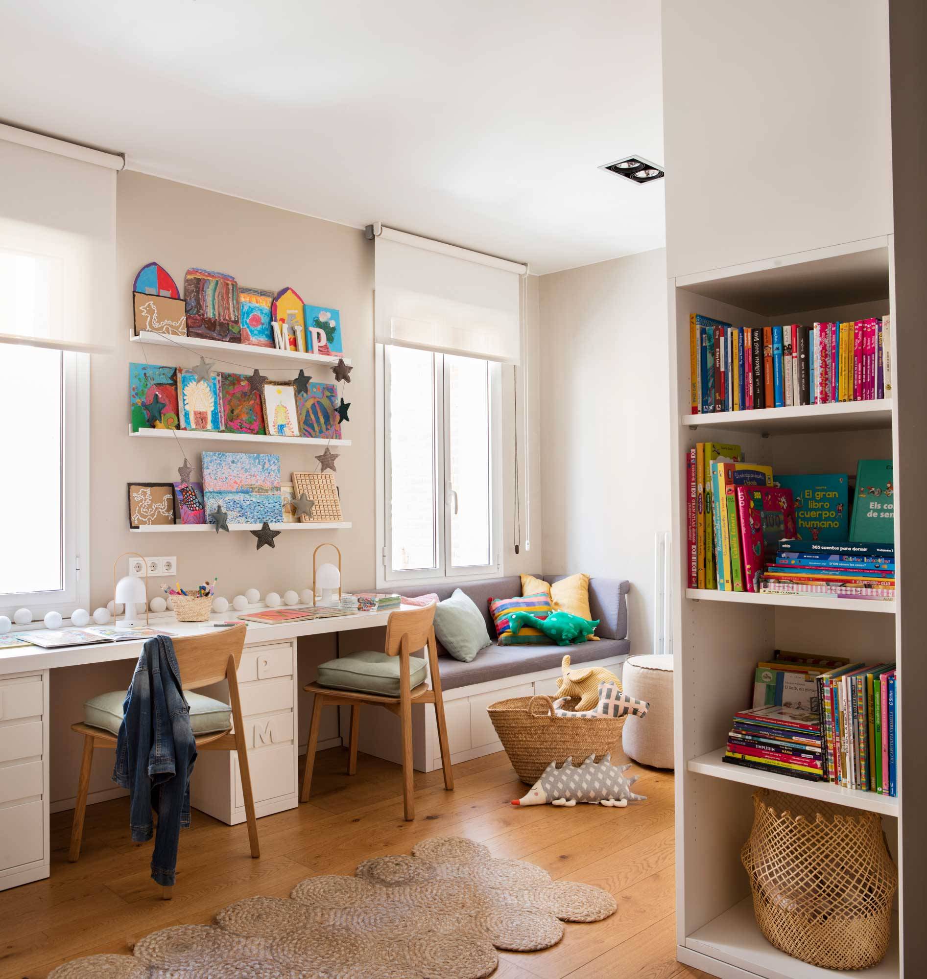 Dormitorio infantil con estantería con libros, escritorio y alfombras de fibra vegetal.