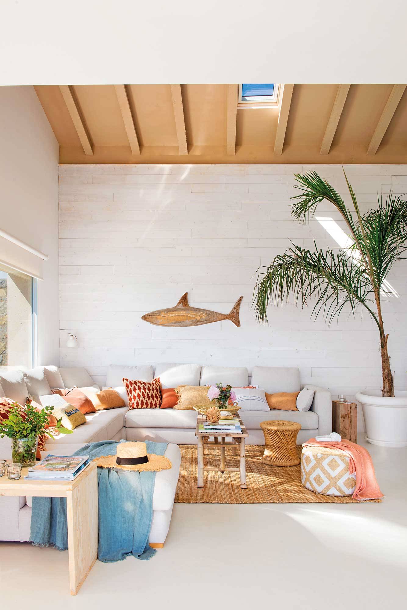 Salón de verano con sofá rinconera y alfombra de fibra natural. 