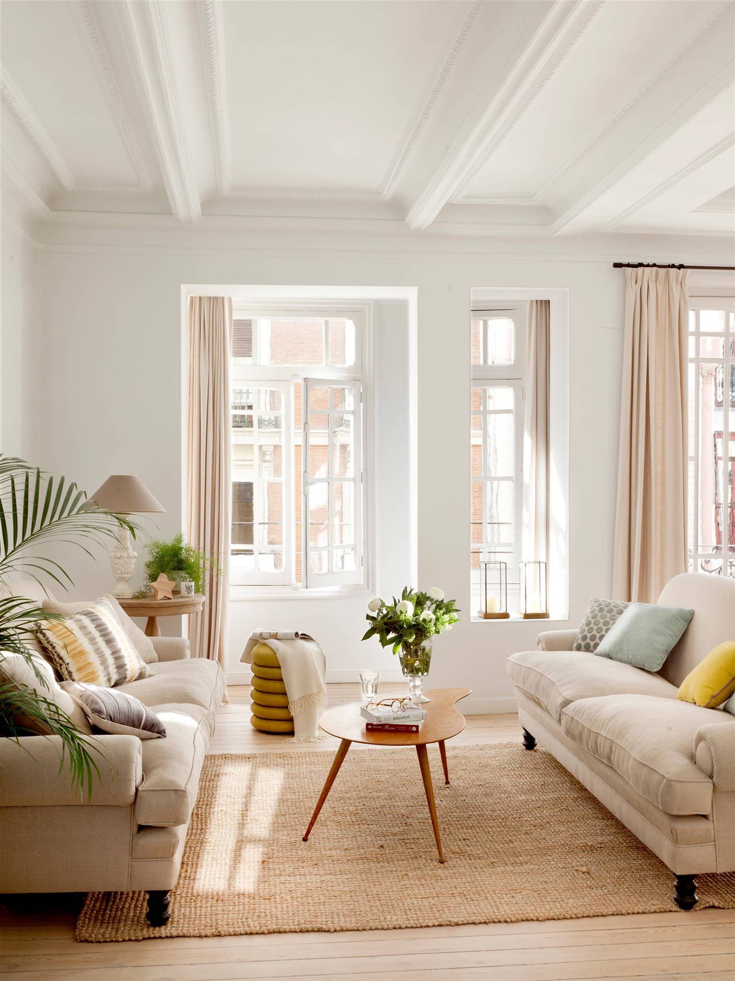 Salón con sofás beige enfrentados y mesas de centro pequeñas de madera.