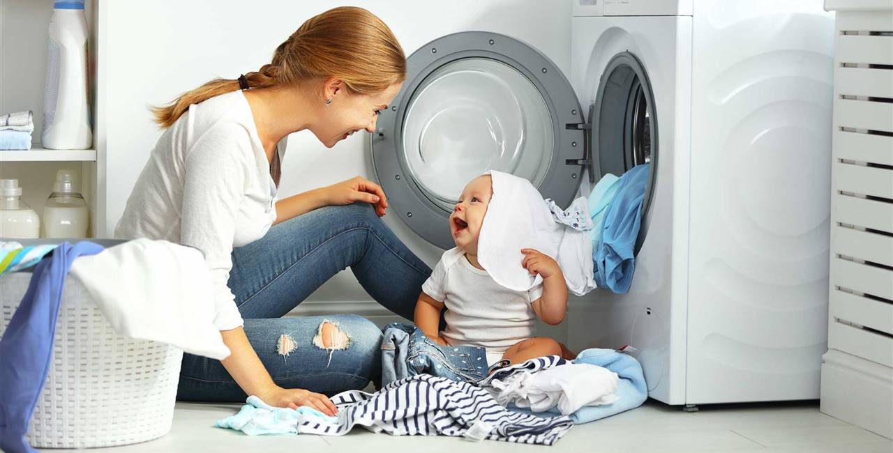 Madre con su bebé poniendo la lavadora-Deposiphoto