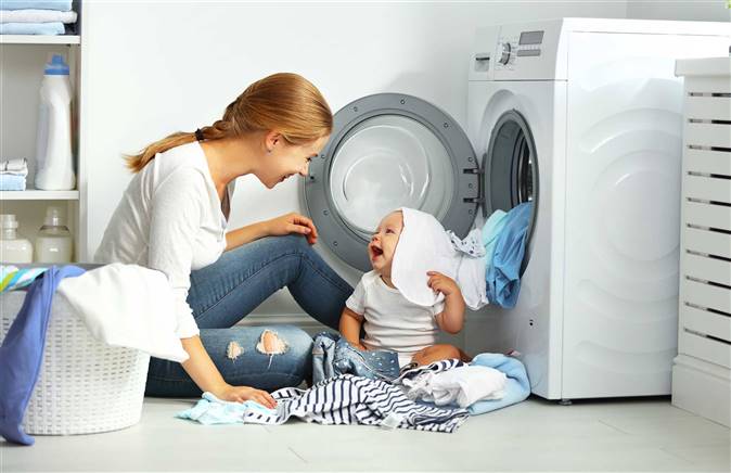Madre con su bebé poniendo la lavadora-Deposiphoto