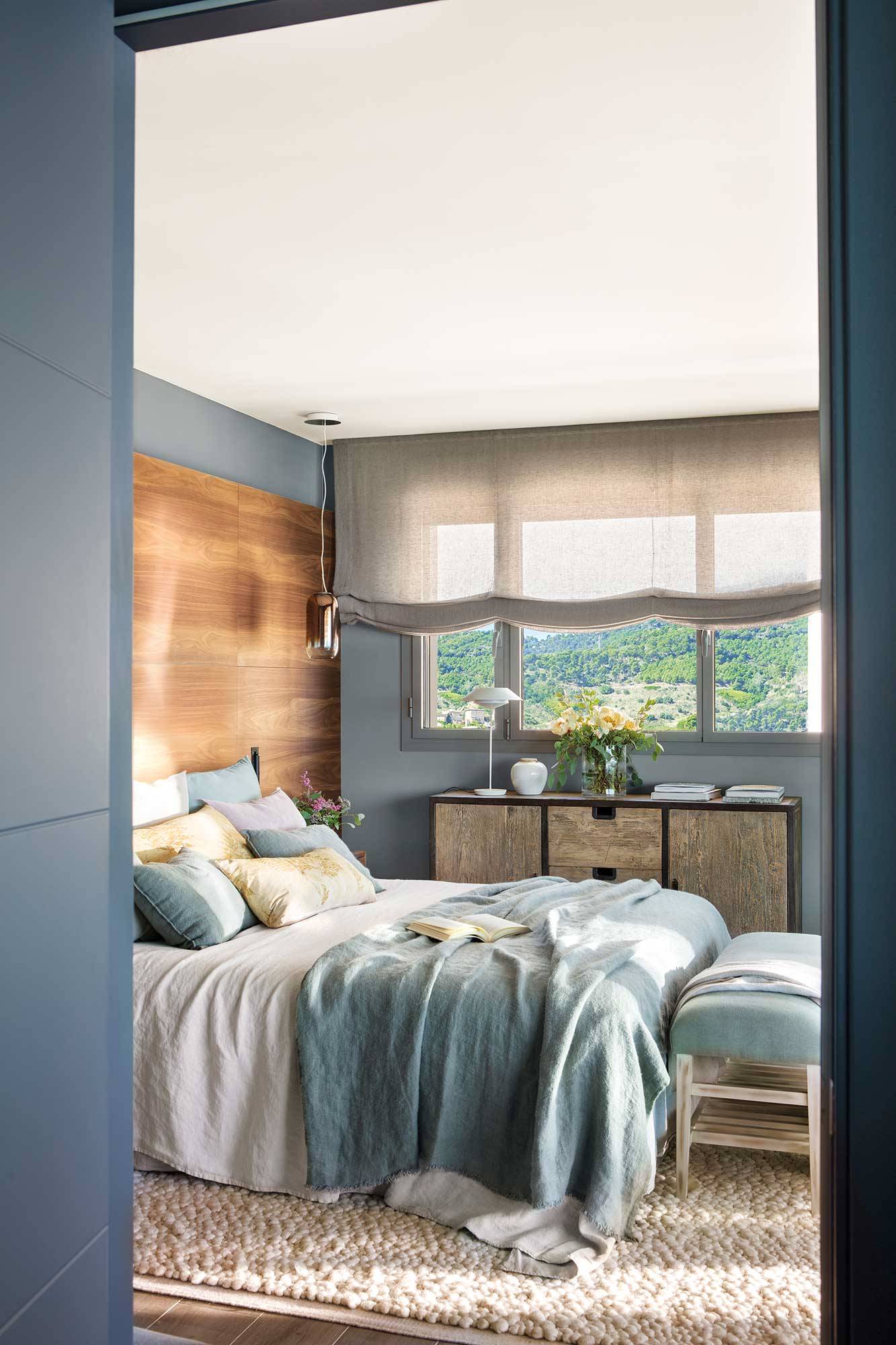 Dormitorio moderno en gris con pared del cabecero revestida de madera. 