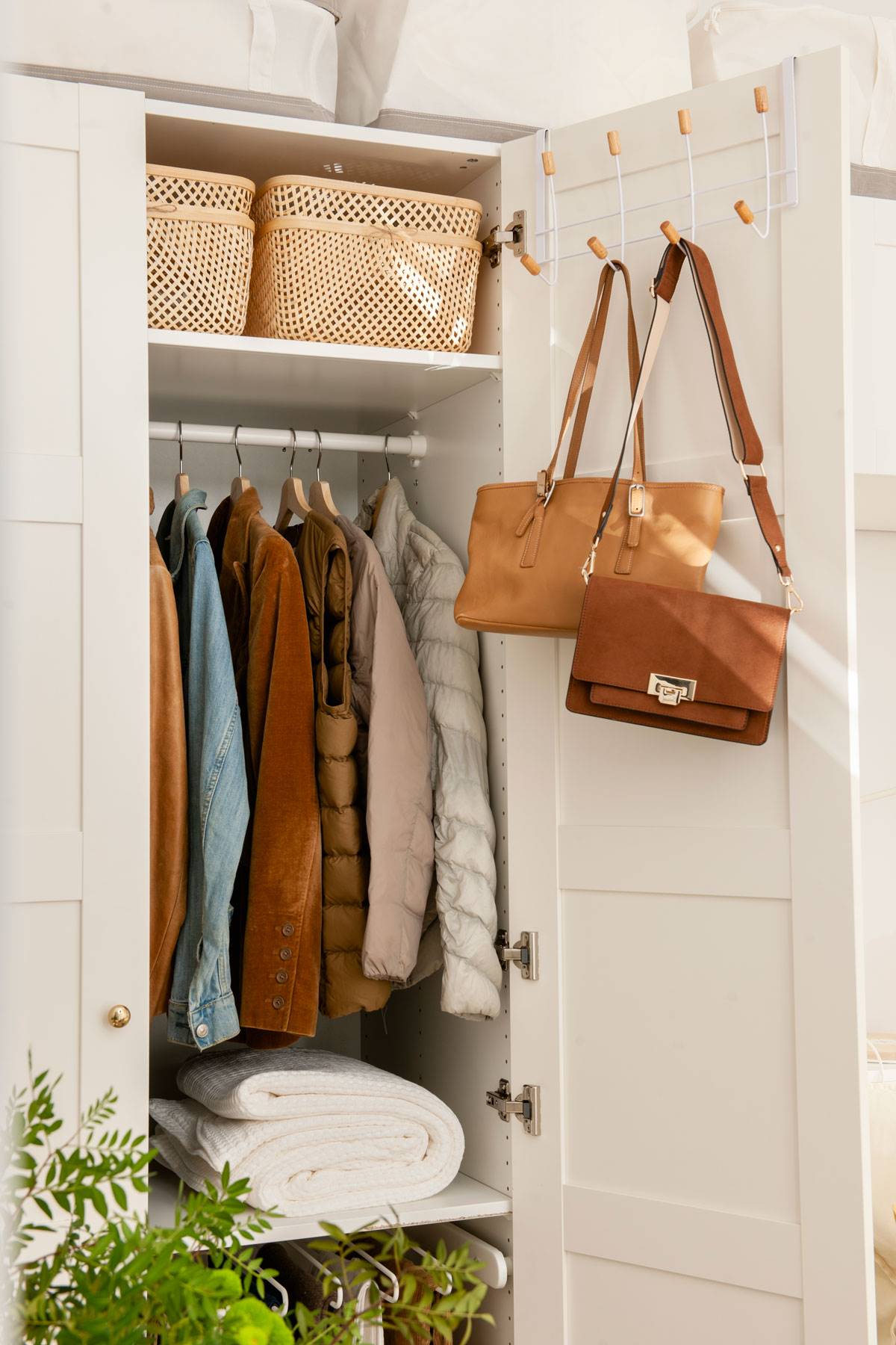 Interior de un armario con colgador de bolsos en la puerta.