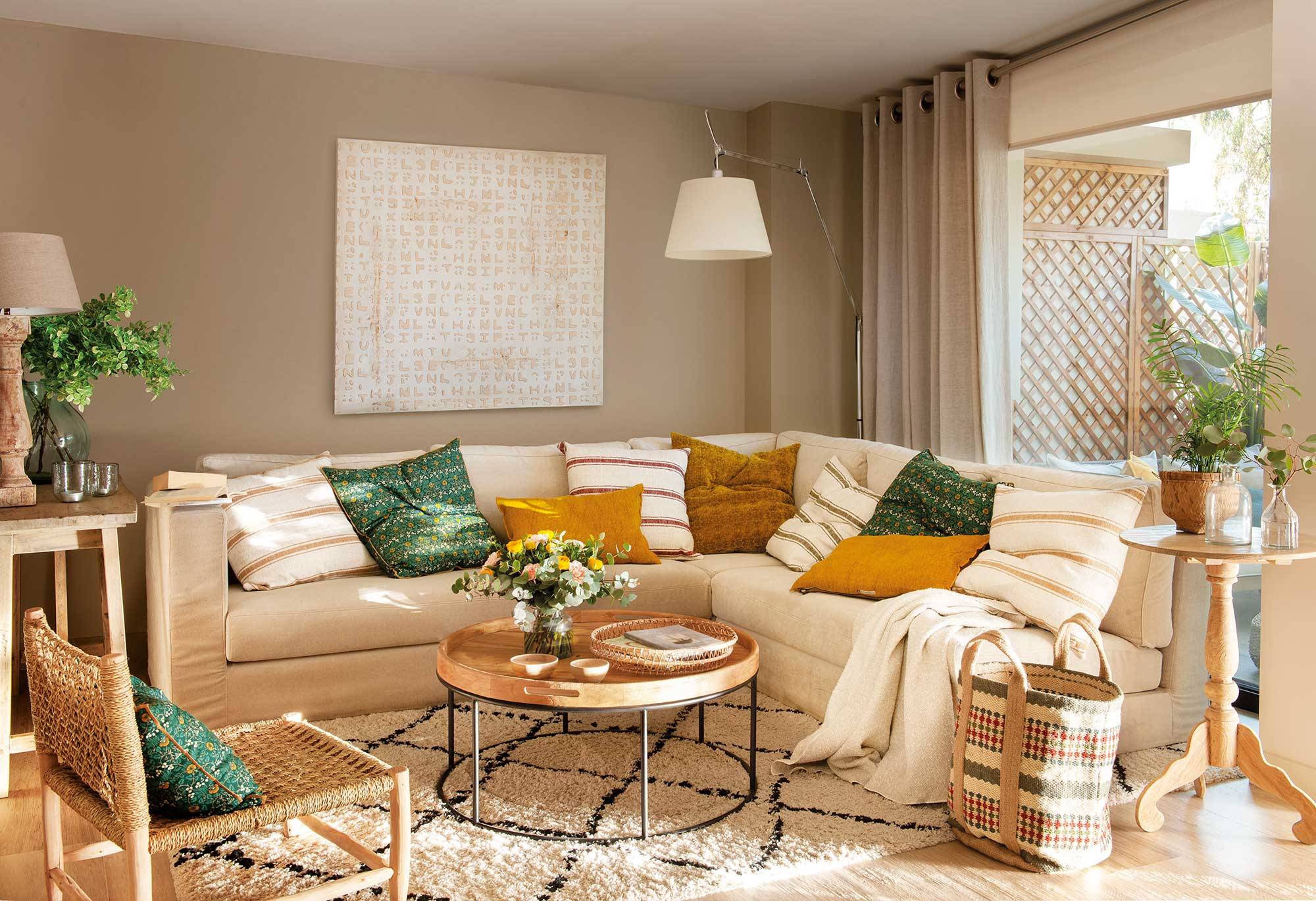 Salón pequeño con sofá en L de color beige y mesa de centro redonda con sobre de madera estilo bandeja y patas metálicas 00521363