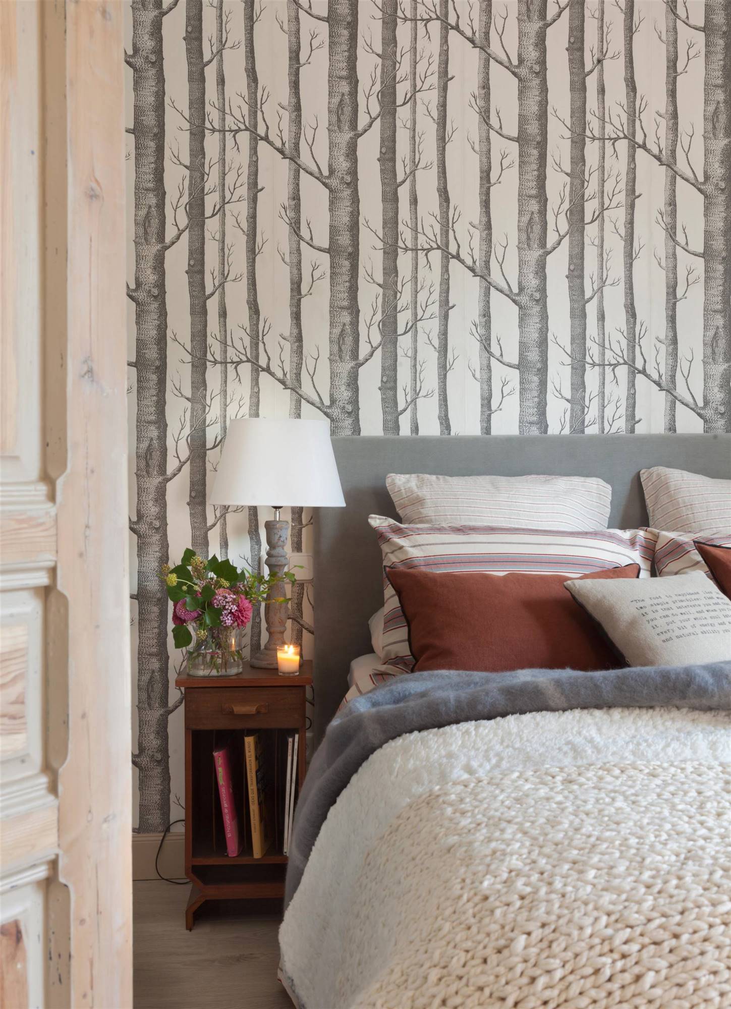 Dormitorio con papel pintado que imita un bosque. 