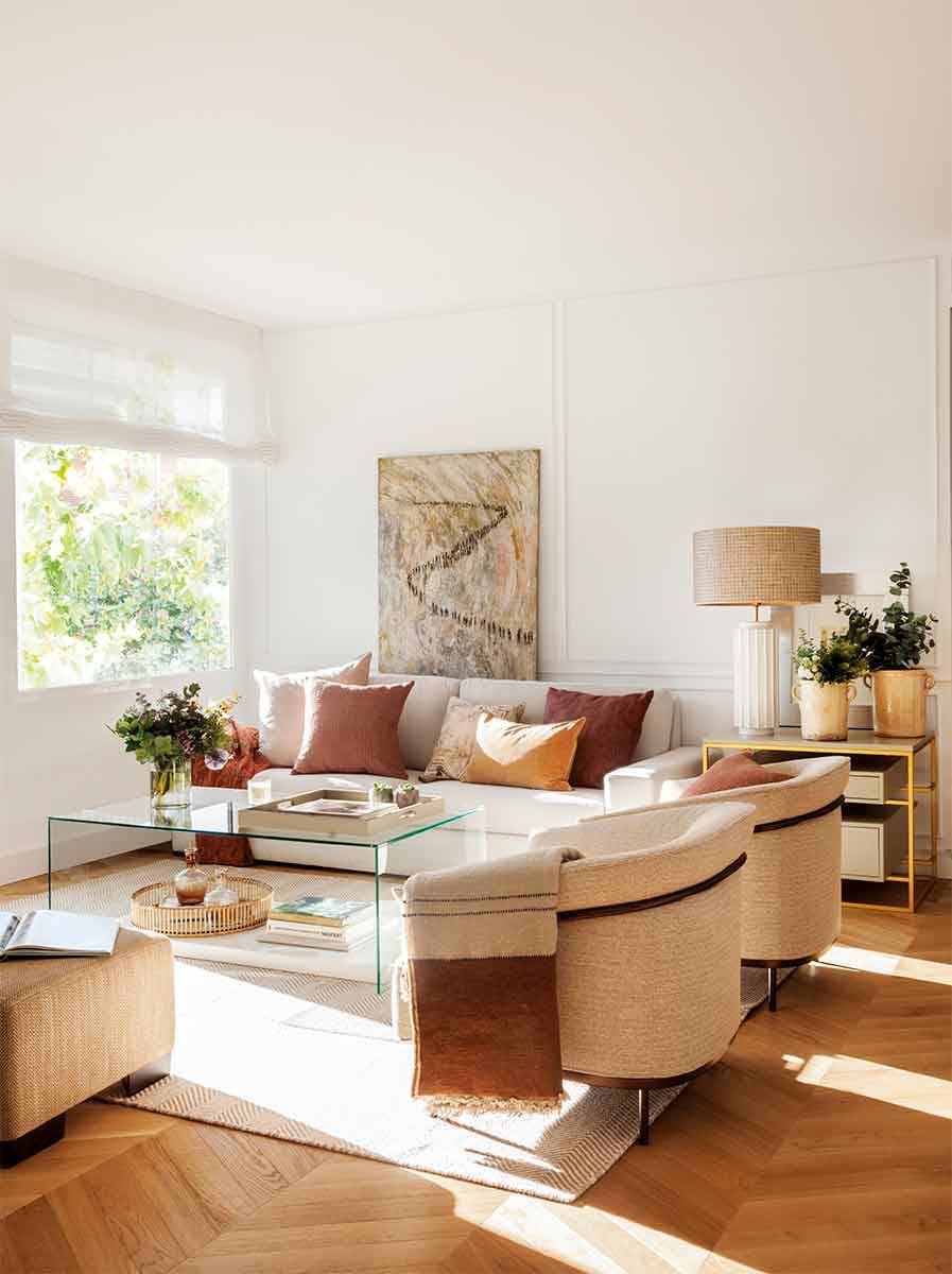 Salón moderno con sofá y butacas de color beige y mesa de centro de cristal.  