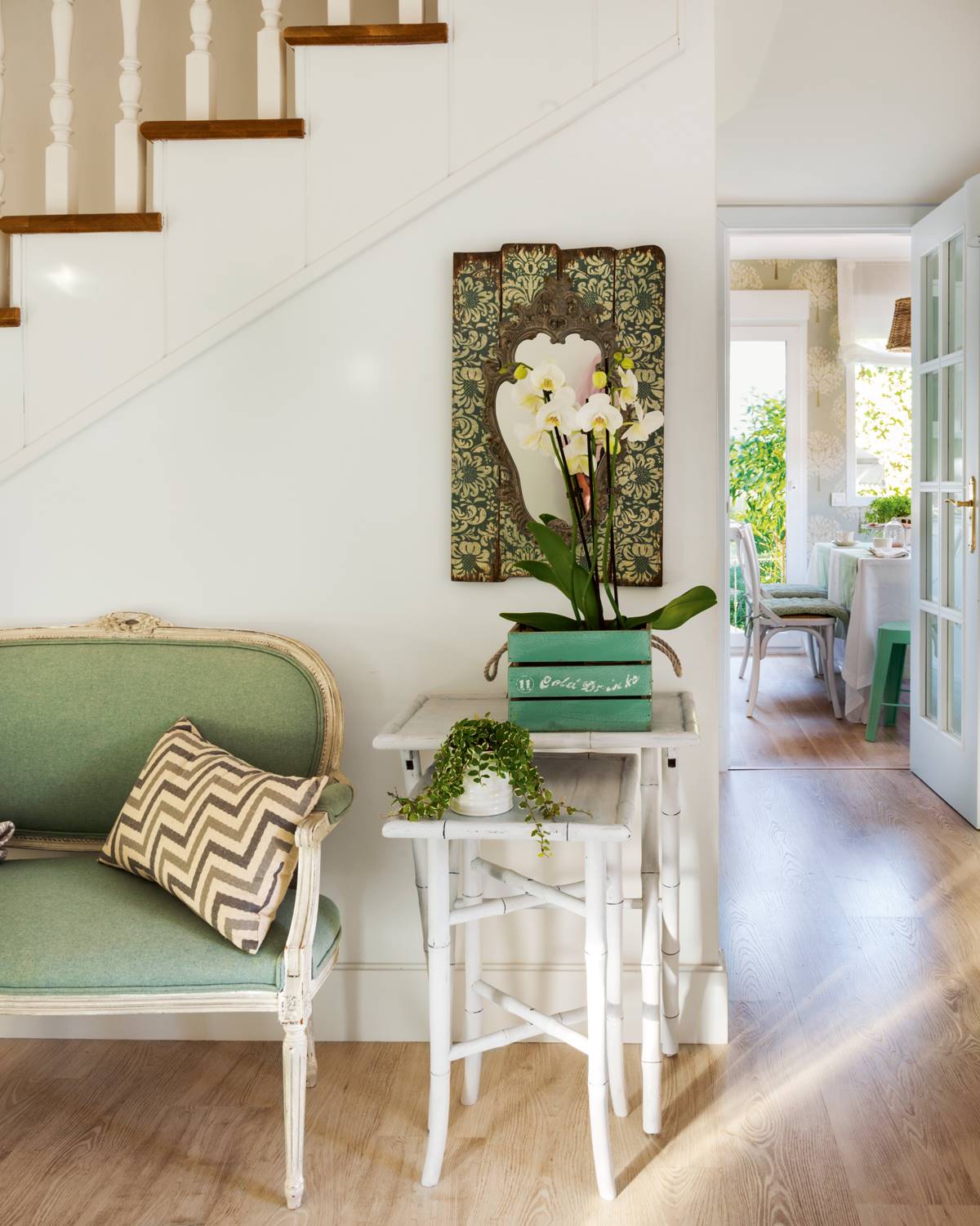 Recibidor con mesas nido, orquídeas y banco clásico tapizado en verde 00412626