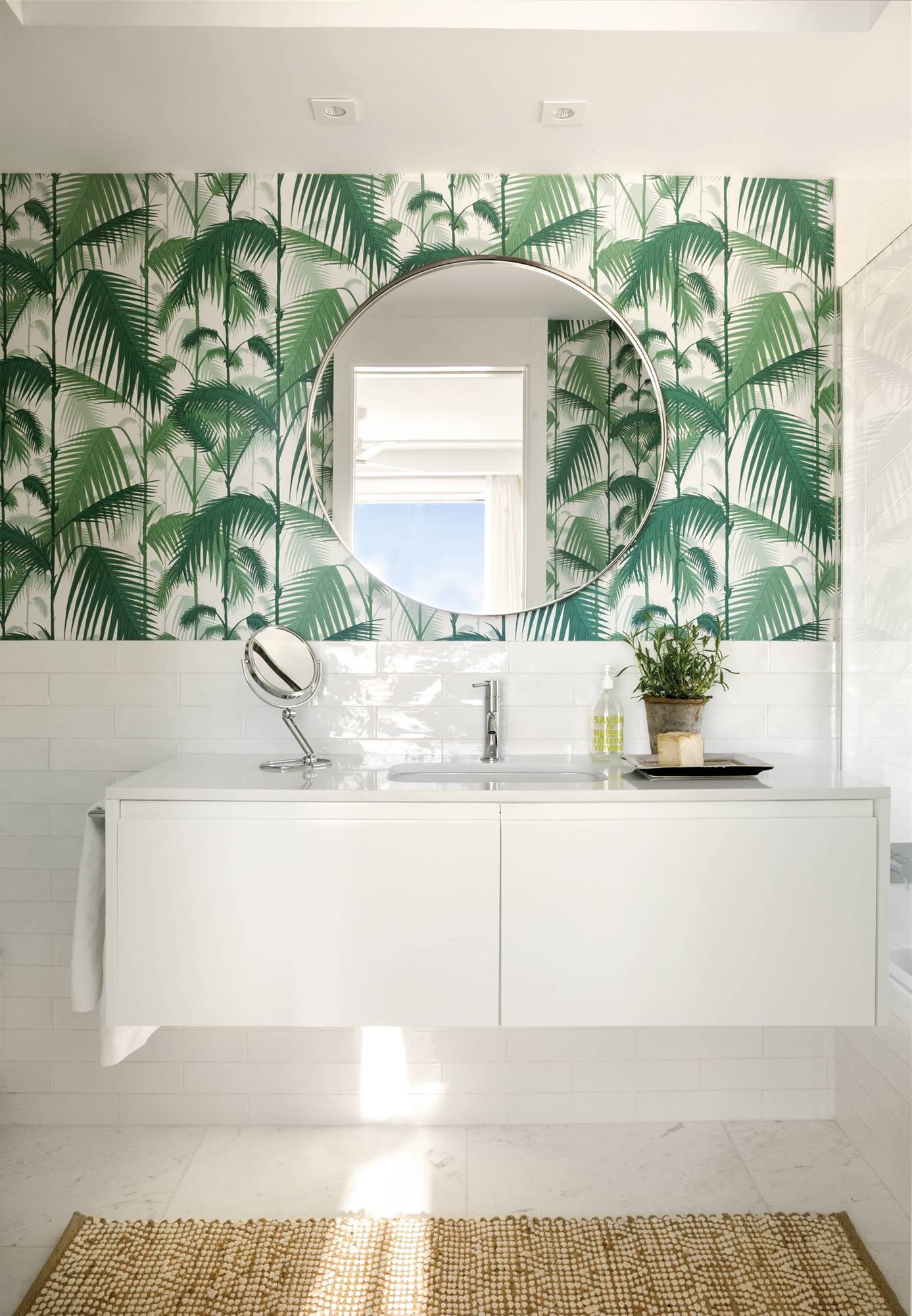 Baño blanco con mueble volado y pared con papel pintado de palmeras 00527437