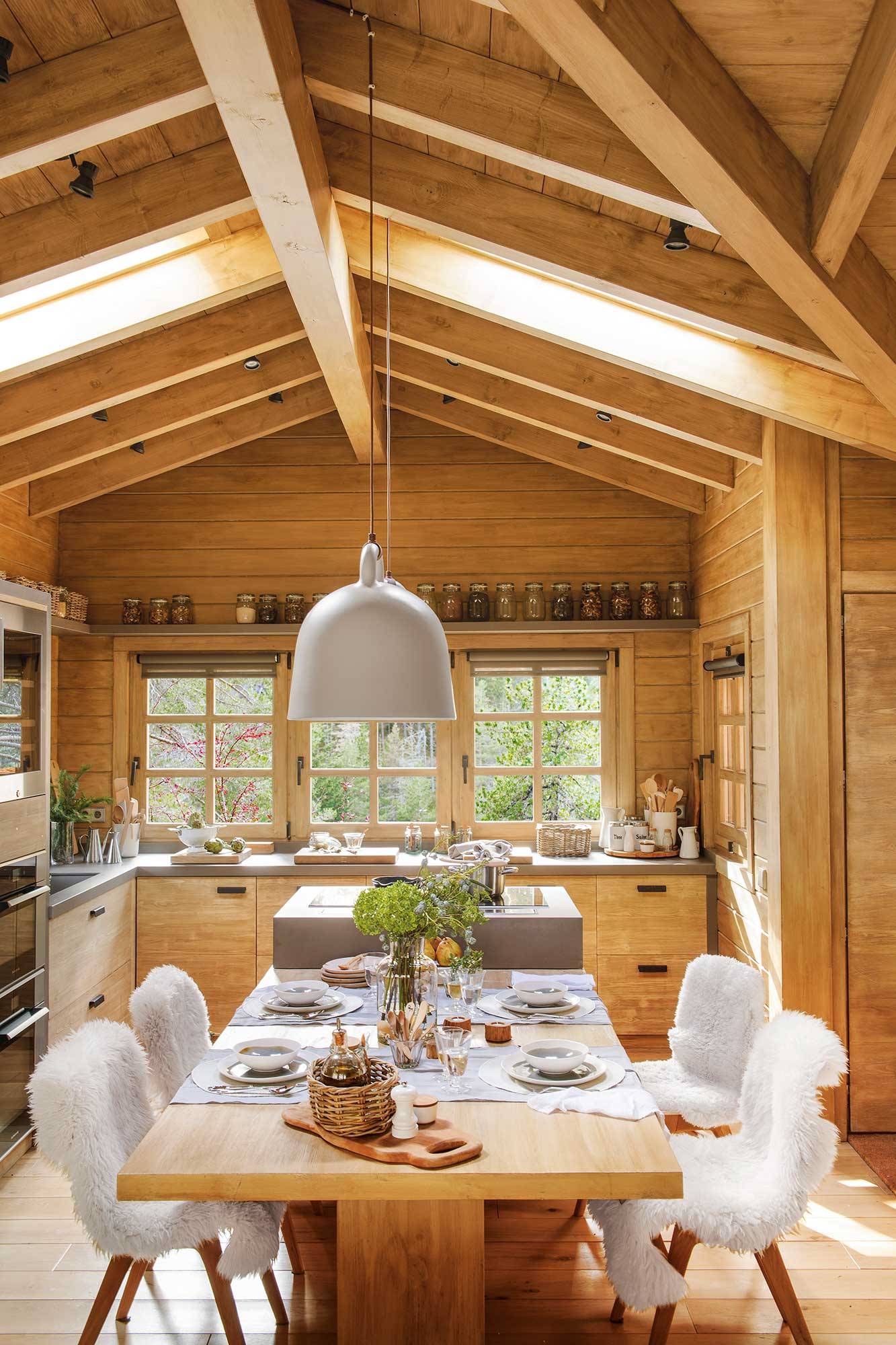 Cocina de madera de casa de montaña con office grande con sllas con plaid de borreguito. 