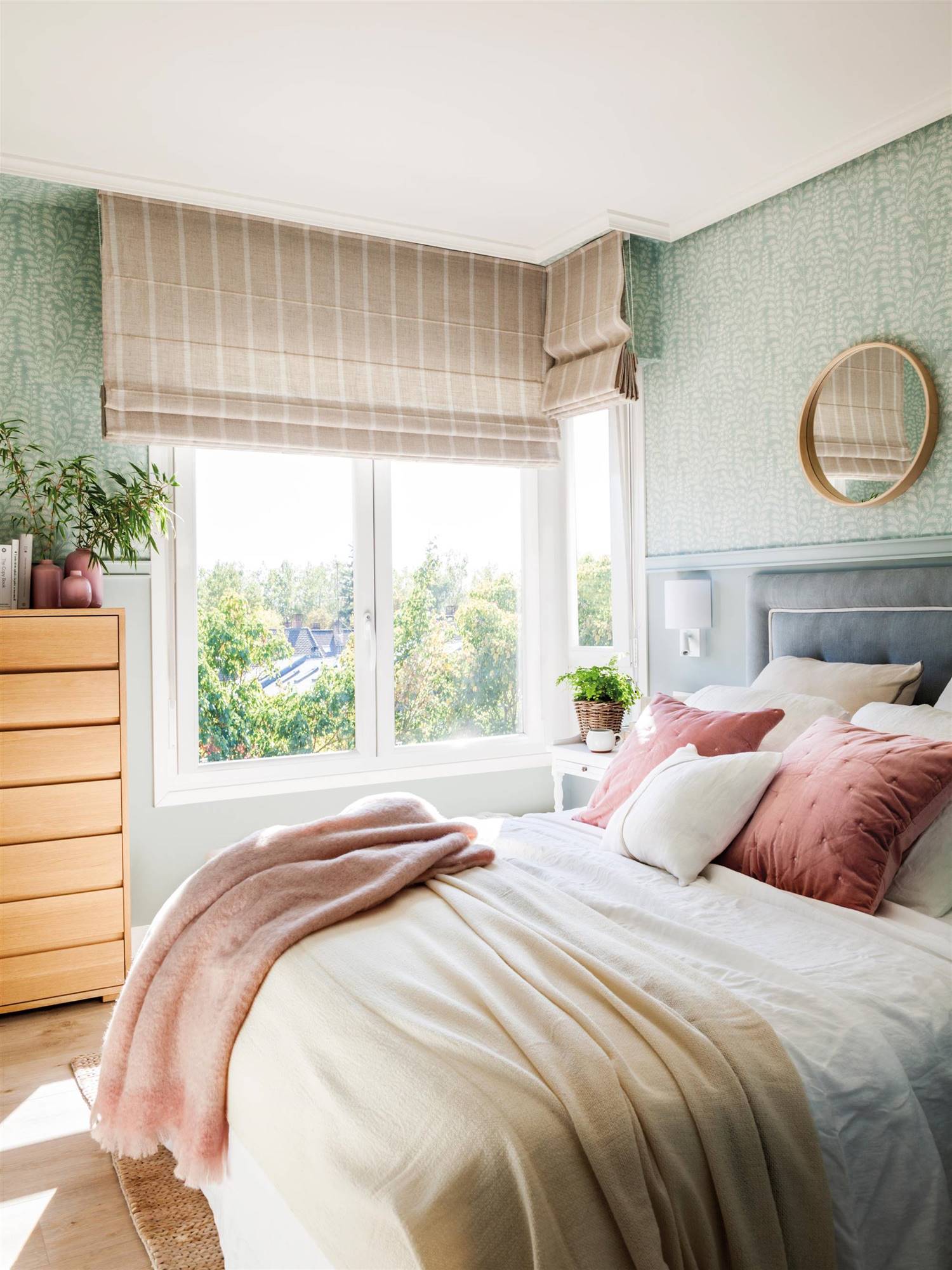 Dormitorio de primavera con papel pintado verde vegetal y estores de rayas en beige.