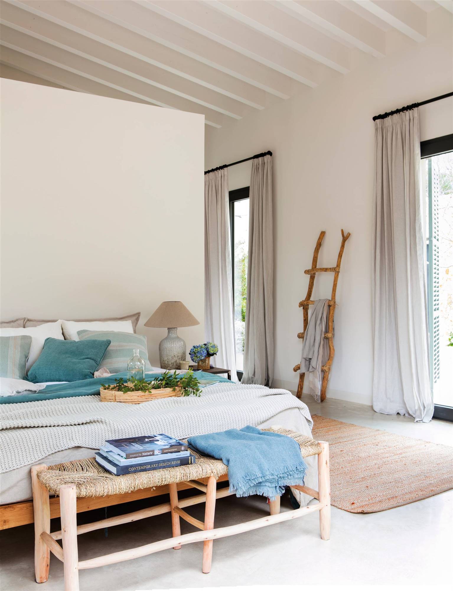 Dormitorio de primavera con escalera decorativa de madera y banco de fibra a los pies.