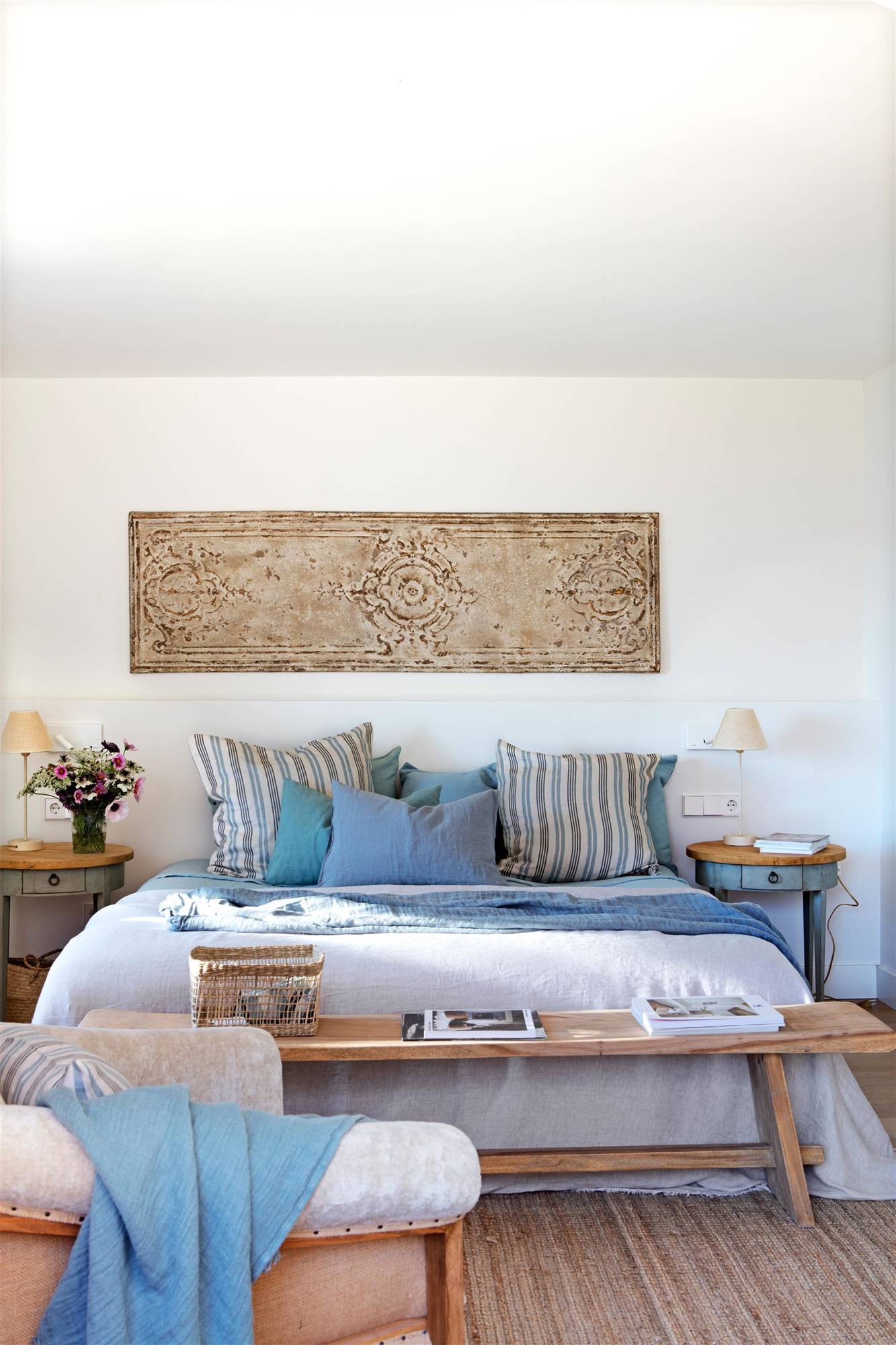 Dormitorio de primavera con cojines de rayas azules y cuadro vintage.