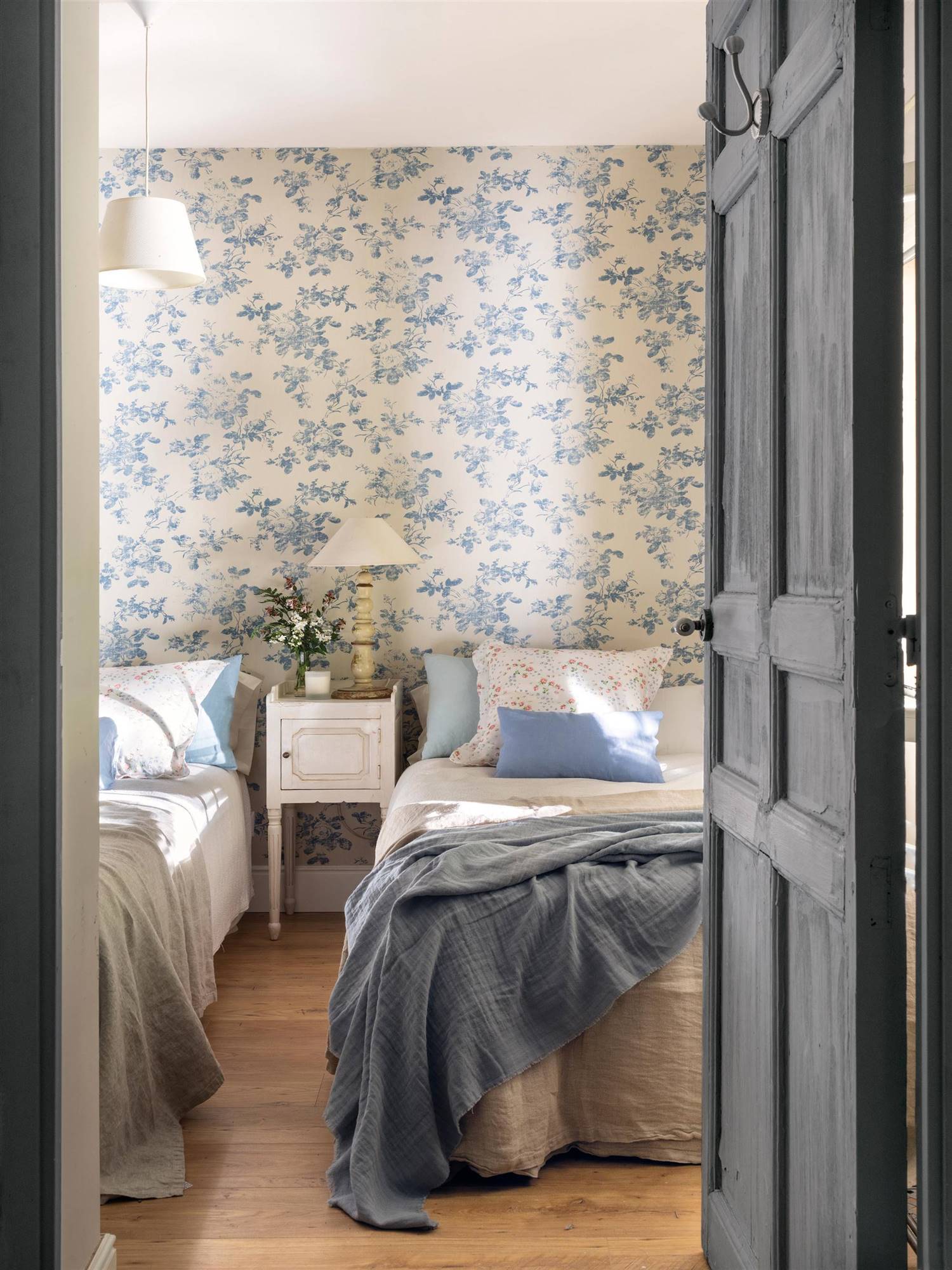 Dormitorio de primavera con papel pintado de flores en azul.