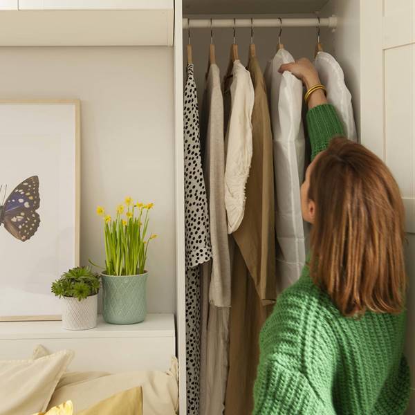 mujer colgando ropa en el armario