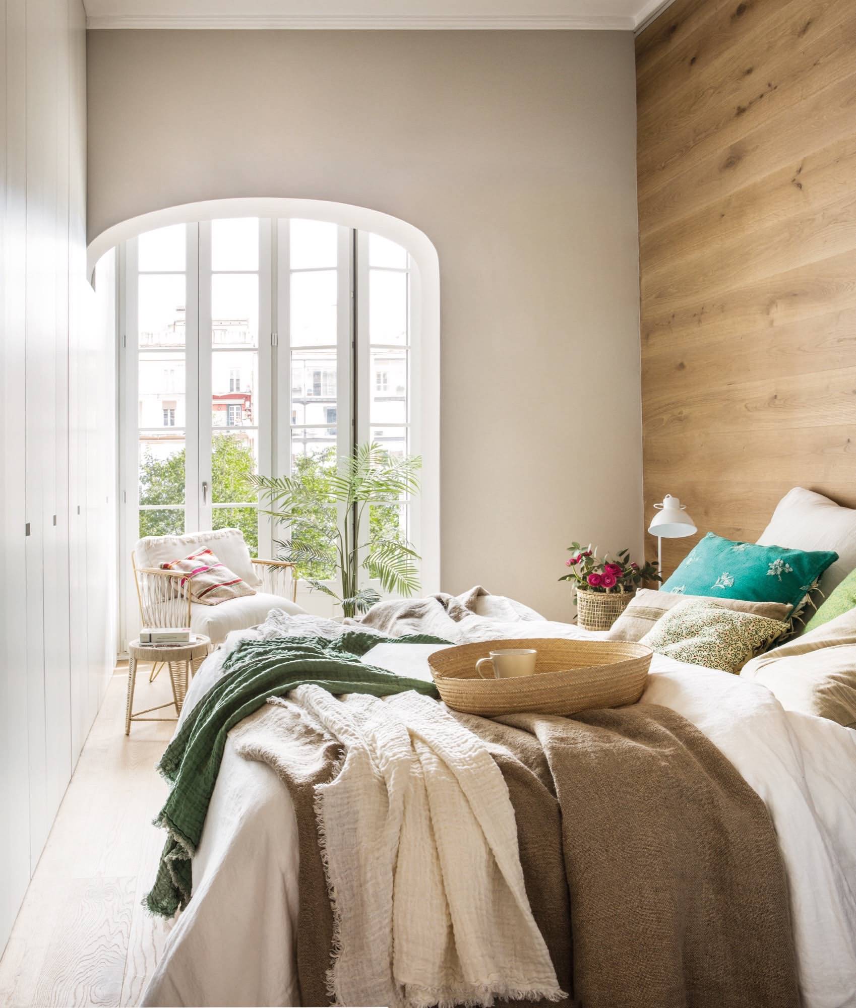 Dormitorio de primavera con cabecero de madera hasta el techo.