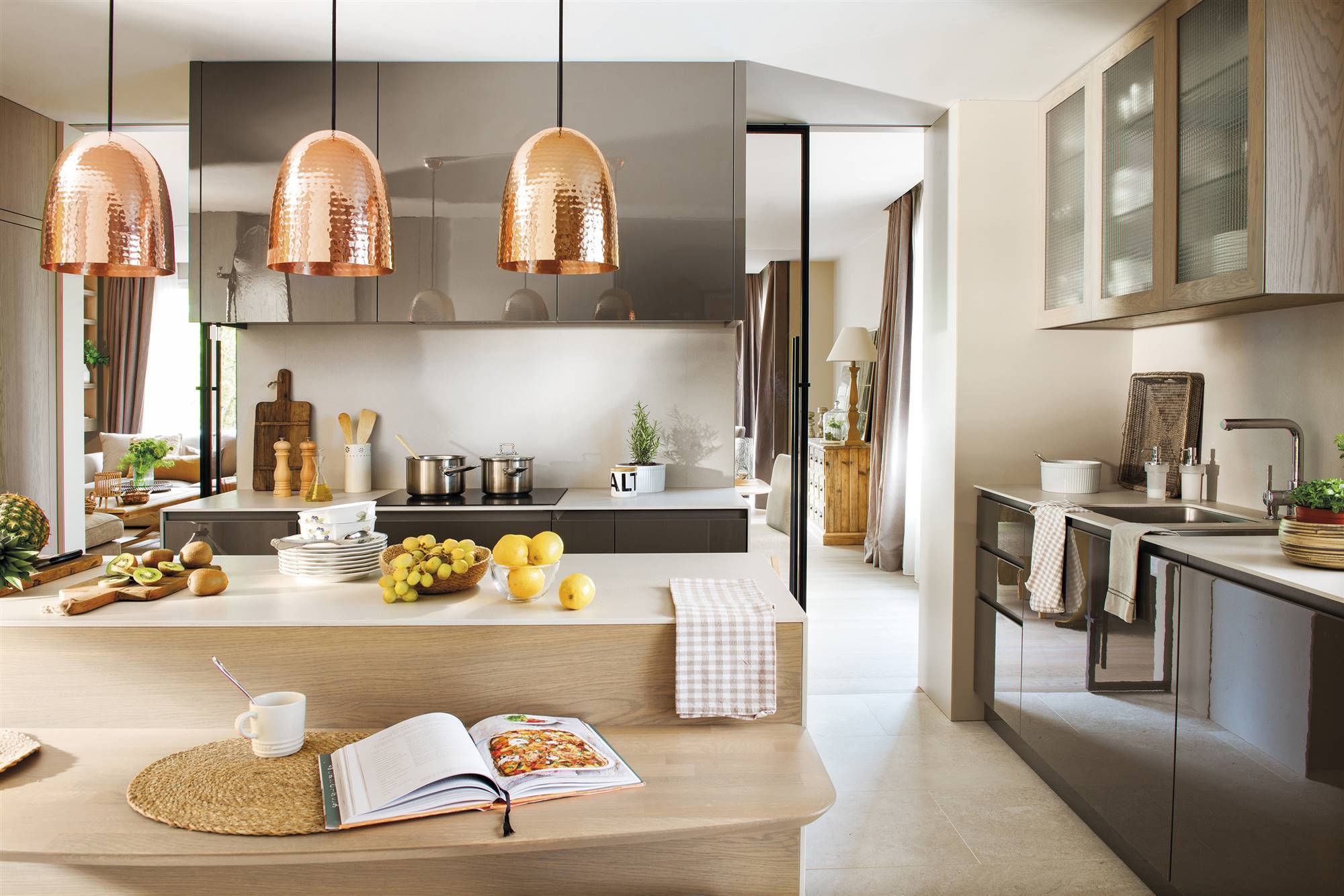 Moderna cocina con mobiliario negro, barra de madera y lámparas de diseño. 