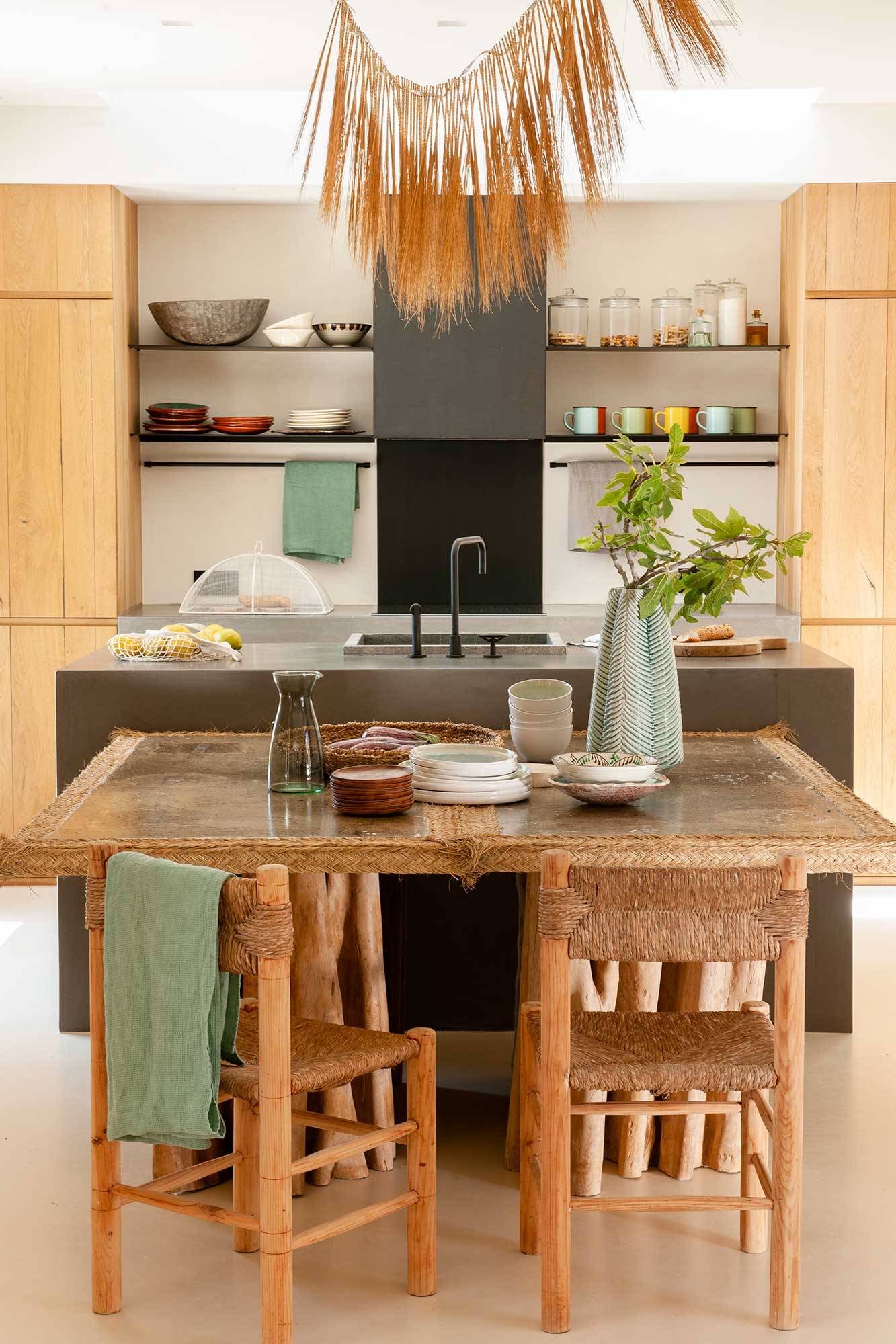 Cocina pequeña y moderna con isla, estantes y office con mesa y sillas hechas de madera y fibras. 