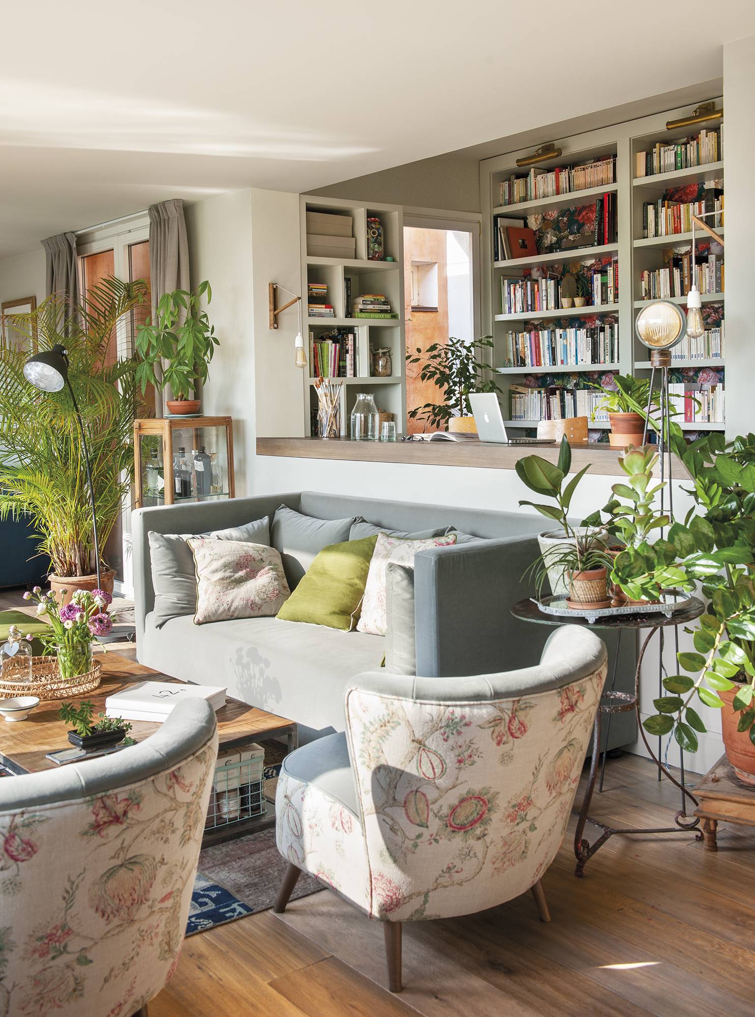 Salón de primavera con sofá, estantería y butacas con tapicería floral.