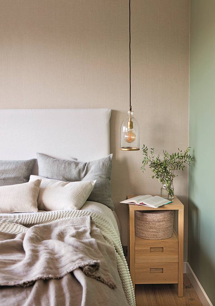 Dormitorio con cabecero de lino desenfundable y mesita de noche de madera. 