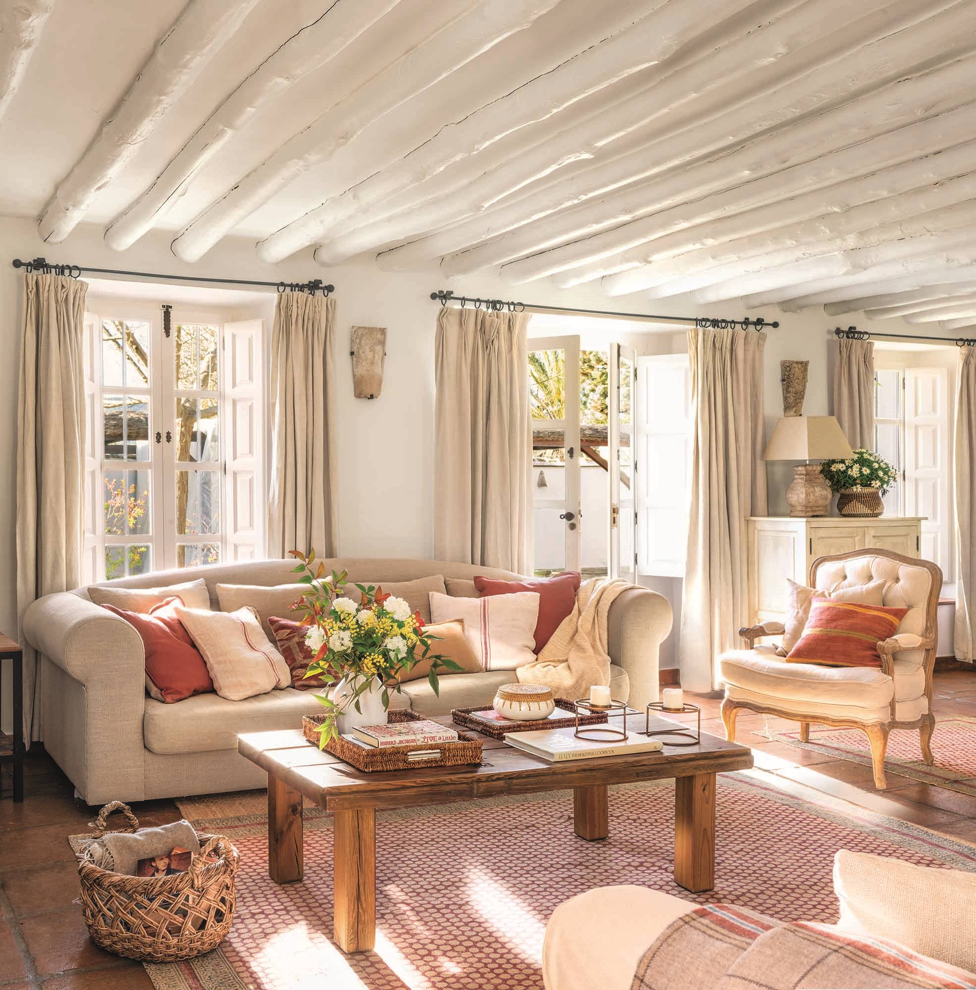 Un salón blanco con muebles locales y toques de color con la madera y las alfombras decorativas. 