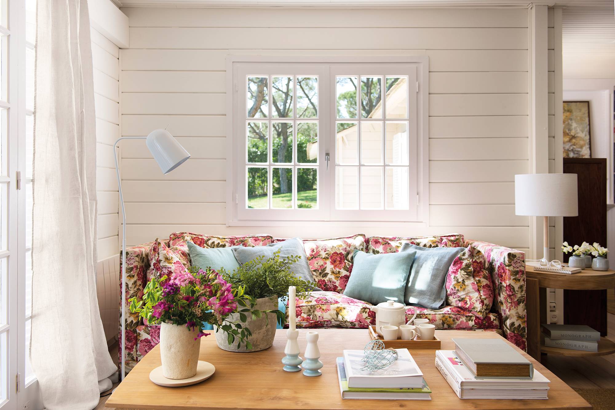 Salón con paredes de lamas de madera blanca y sofá tapizado a flores_ 00458414