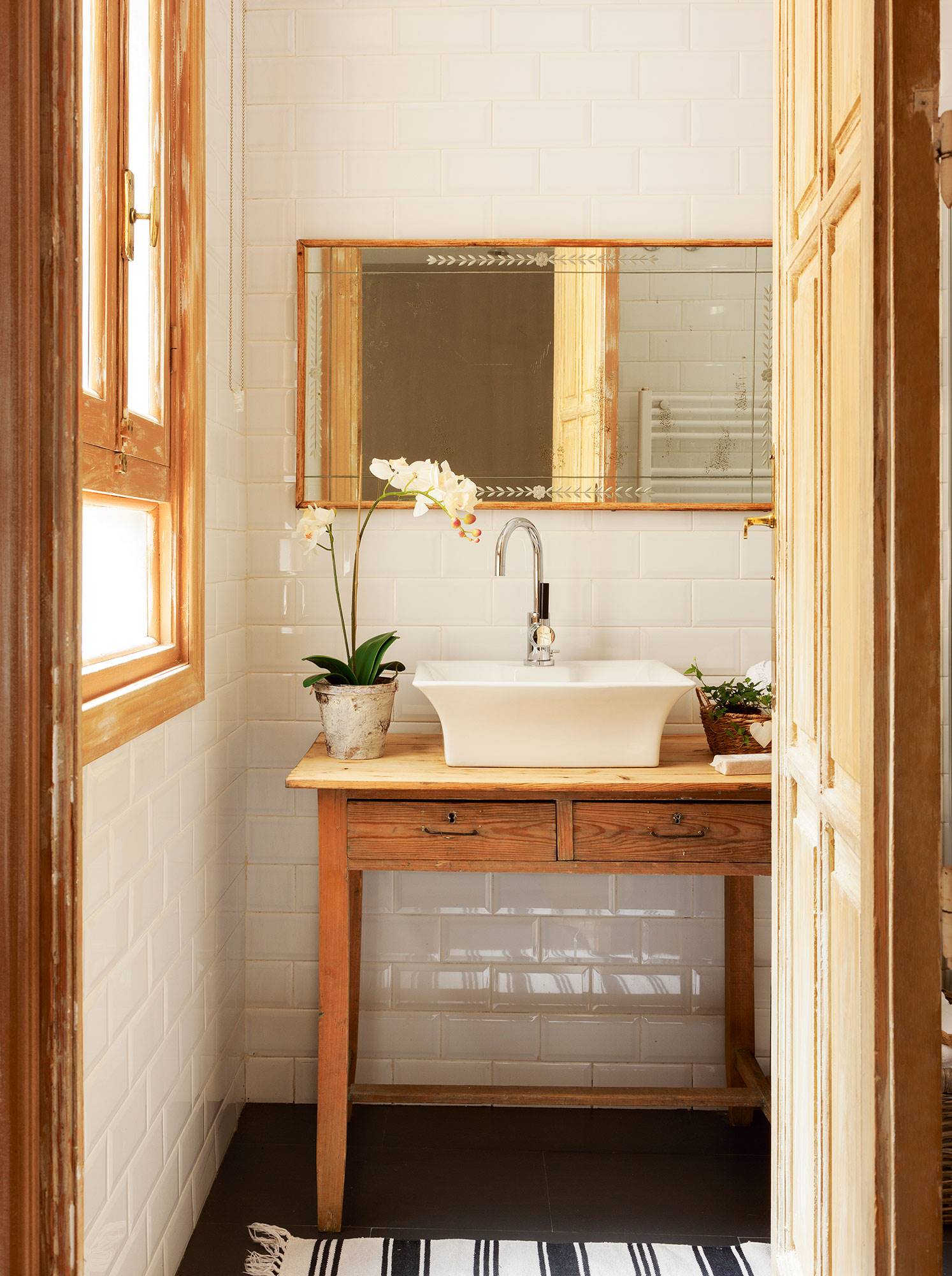 Baño pequeño de estilo rústico con azulejos tipo metro blancos, espejo antiguo con marco de madera y mesa recuperada de madera.