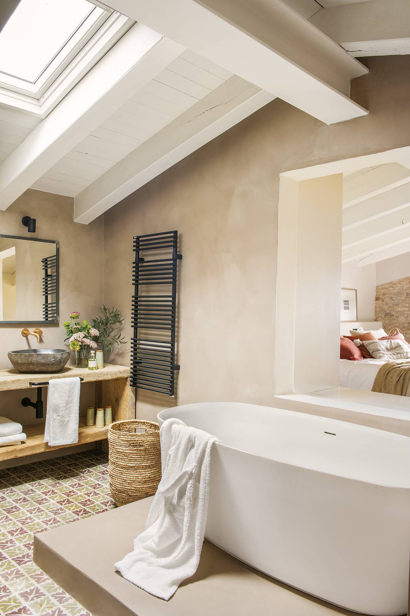 Baño con bañera exenta, azulejos y mueble de madera.