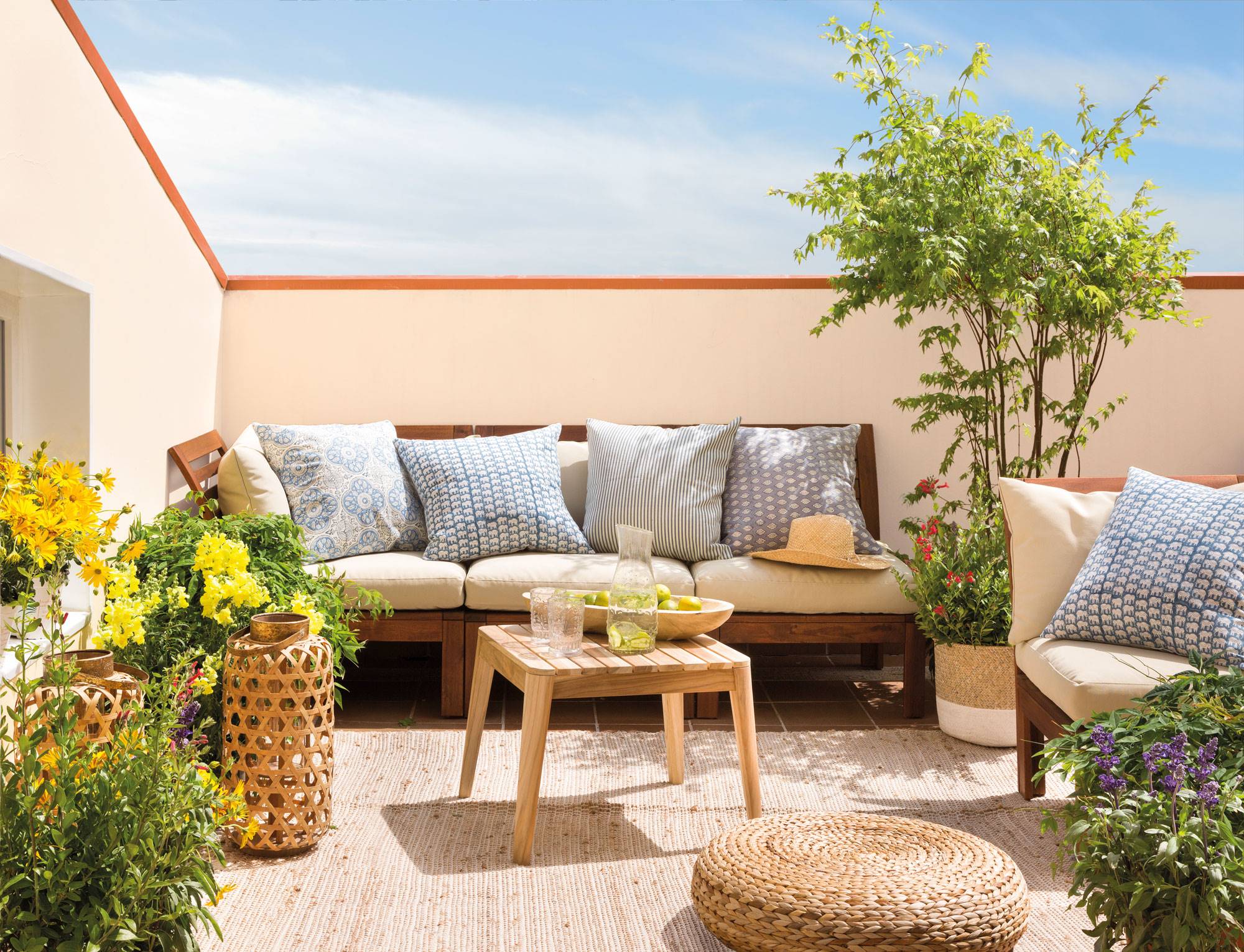 Terraza con plantas, sofá, mesa de centro de madera y puf de fibras 00462089