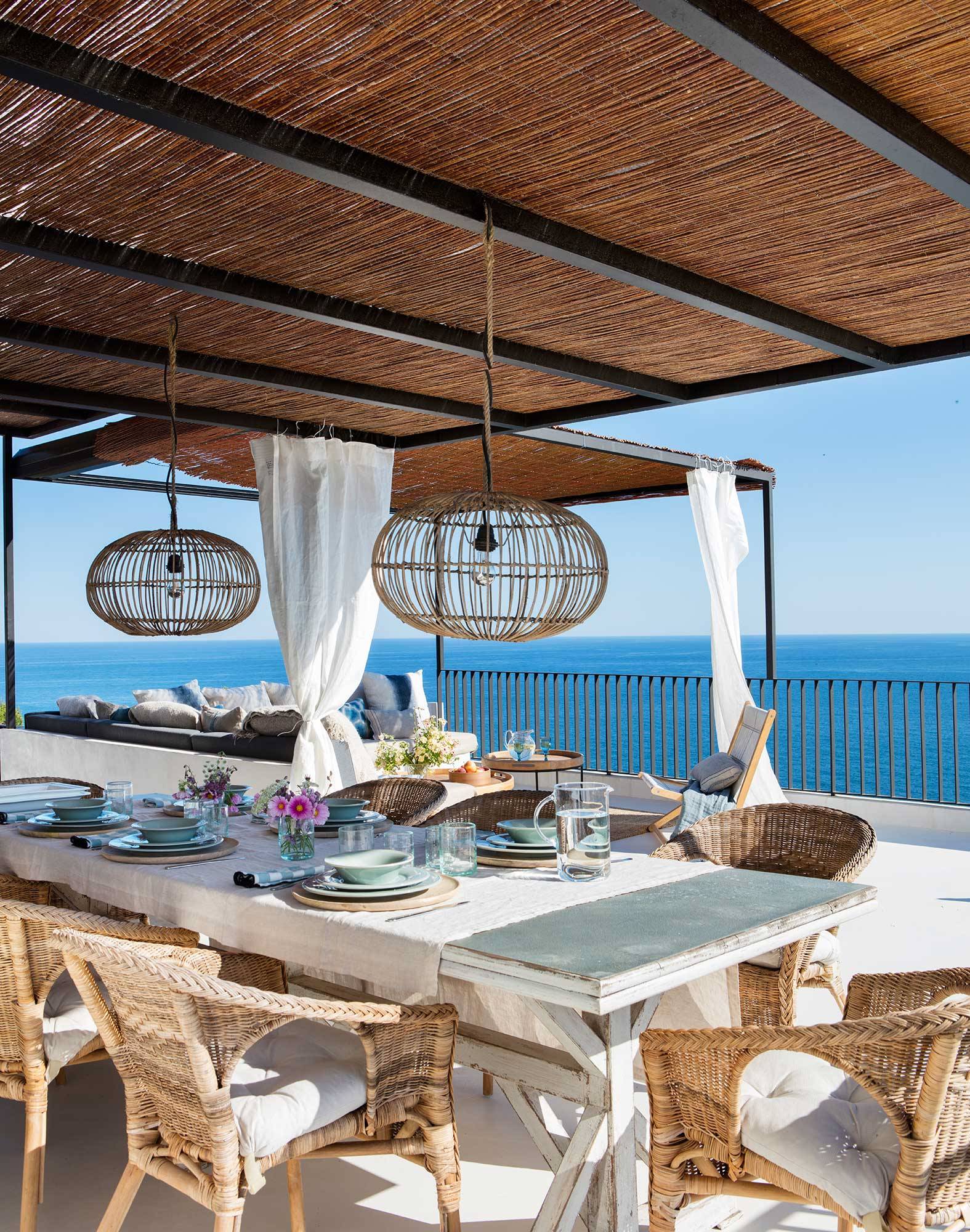Terraza con vistas al mar con comedor exterior y salón de verano.