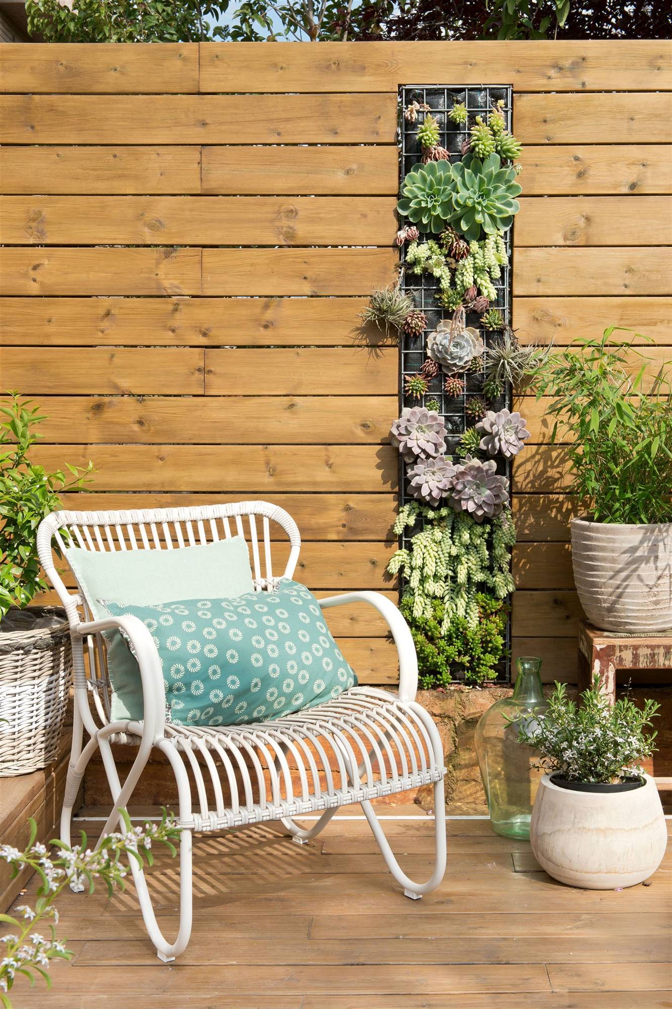Terraza panelada de madera con jardín vertical y butaca blanca 00406475_O