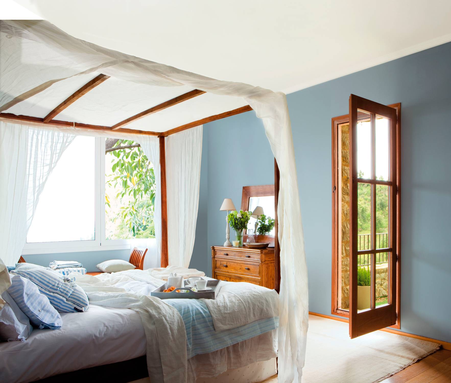 Dormitorio azul con cama con dosel de madera 00319828