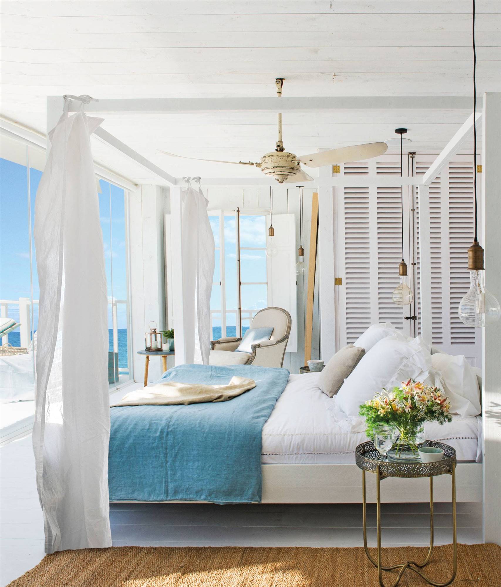 Dormitorio grande de casa de verano en blanco con cama con dosel, toques de azul y vistas al mar 00461872